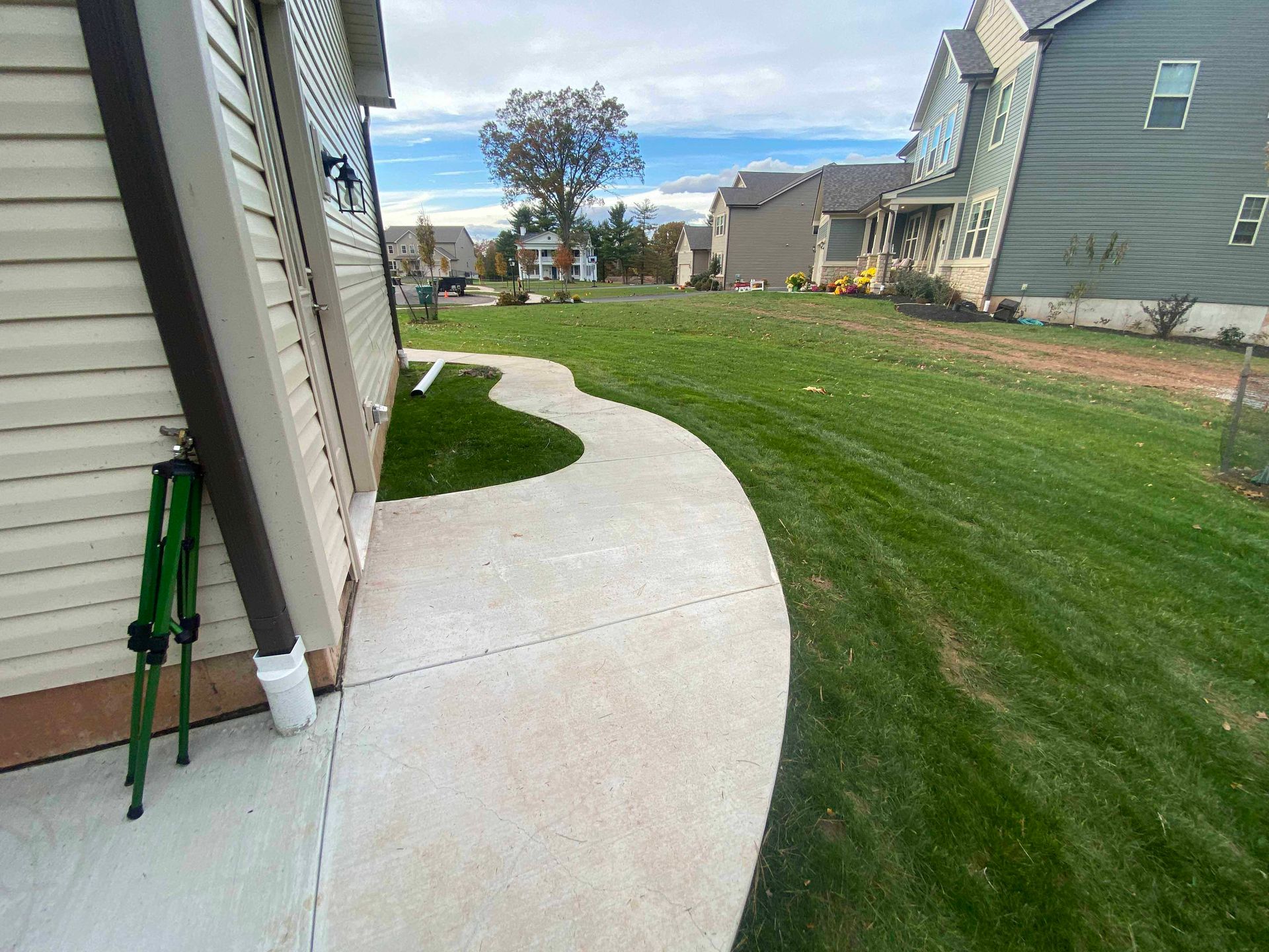 A concrete walkway leading to a house with a lush green lawn.