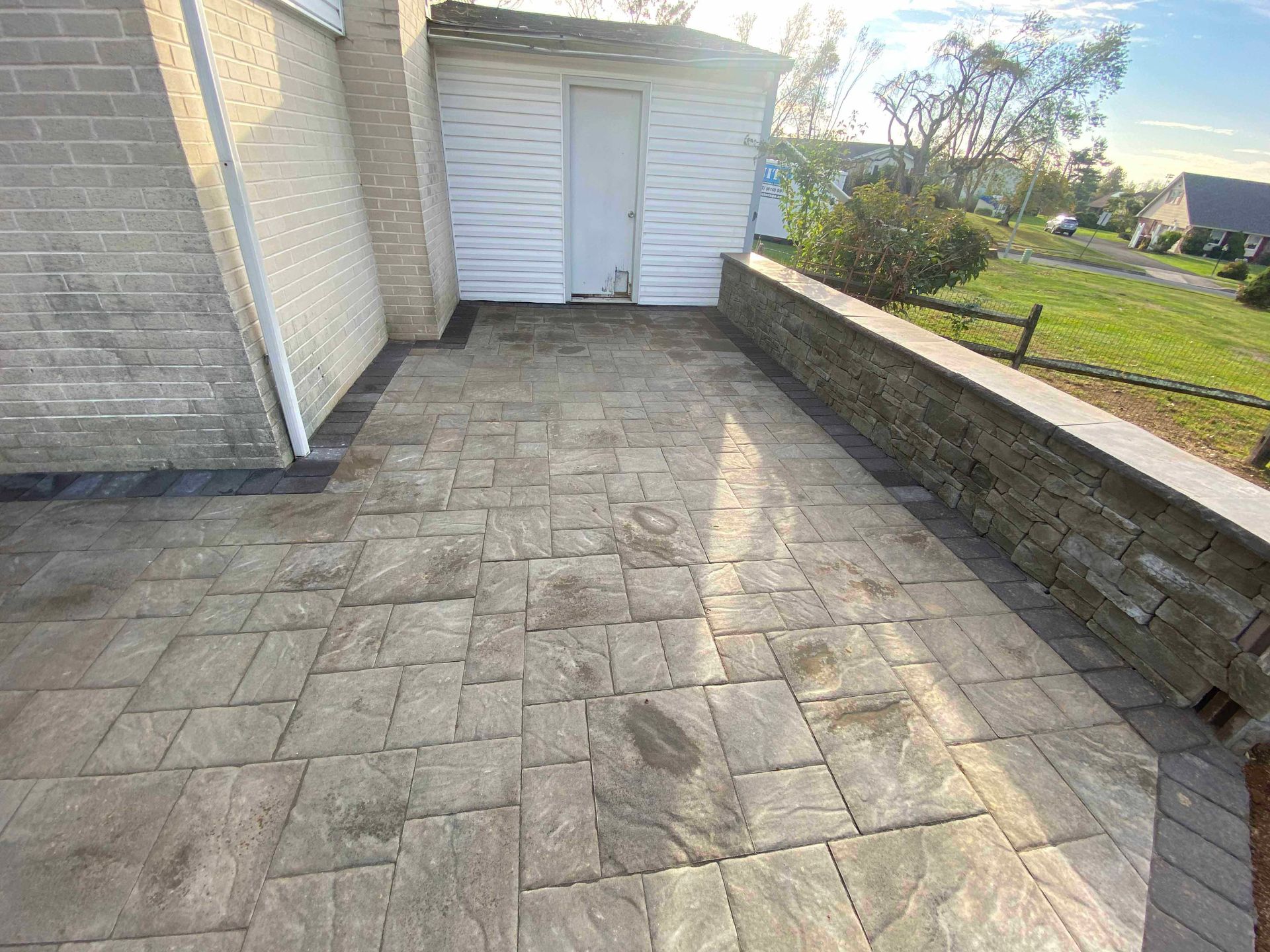 A patio with a brick wall and a white building in the background.