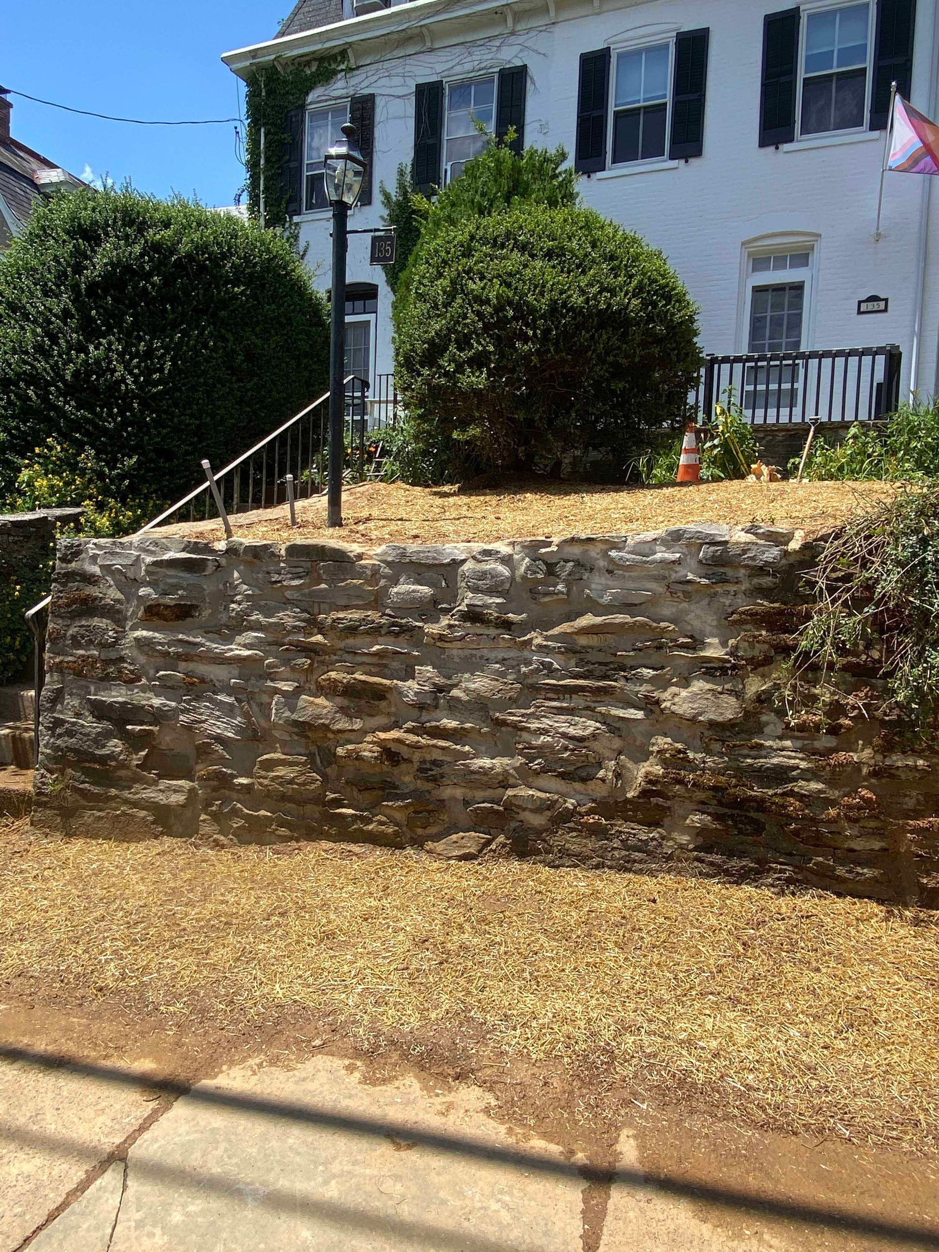 A large white house with a stone wall in front of it