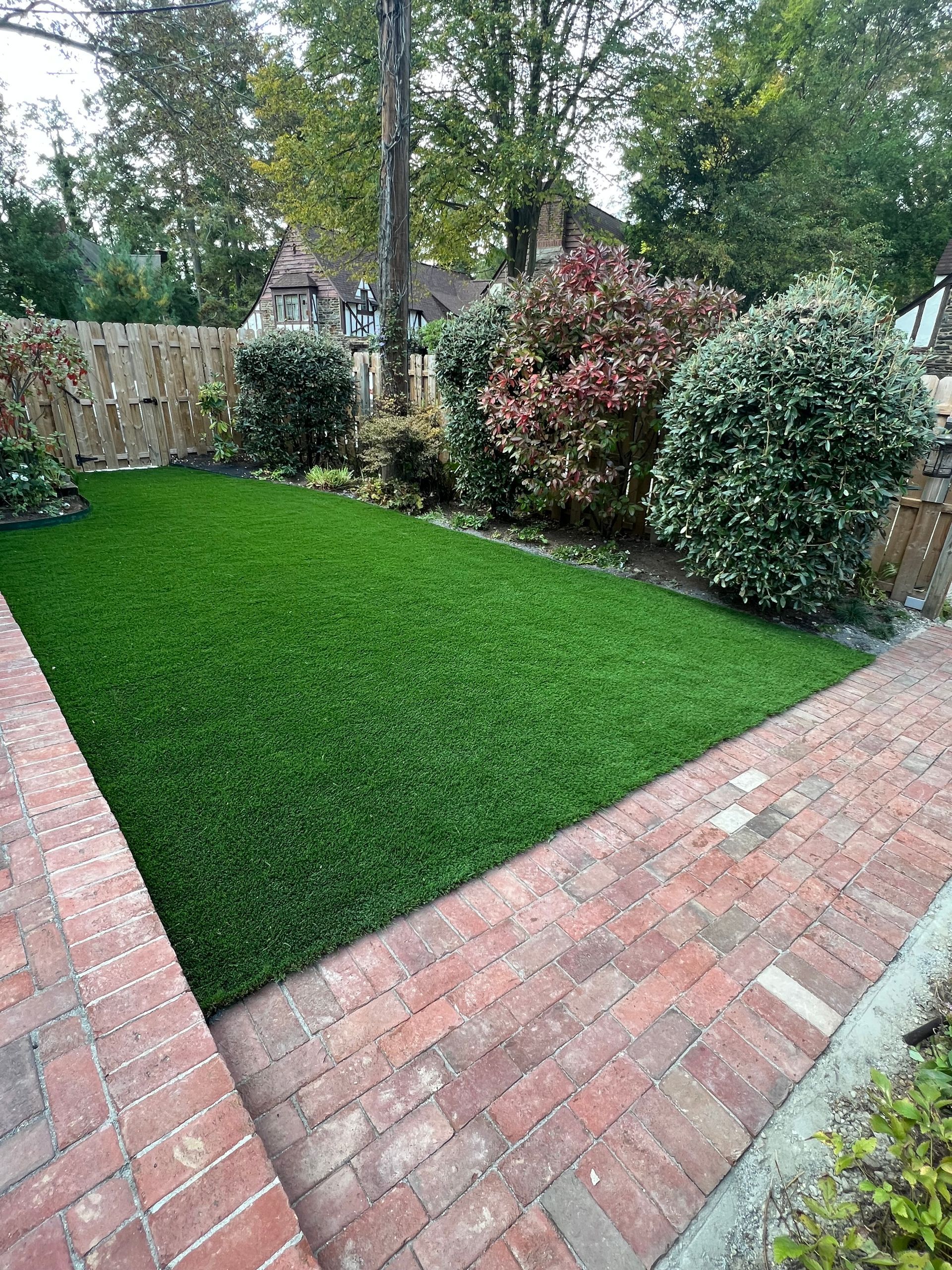 A backyard with a brick walkway and a lush green lawn.