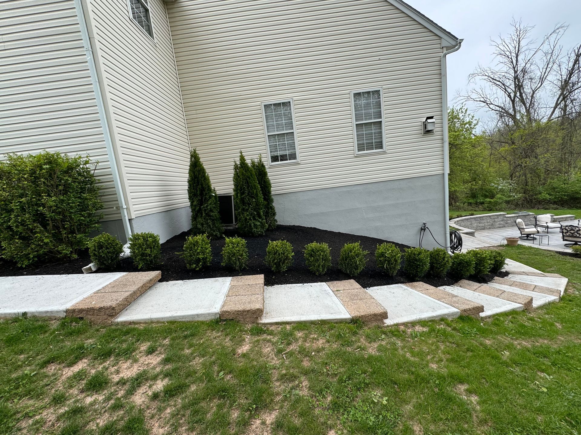 A house with stairs leading up to it and a lush green yard.