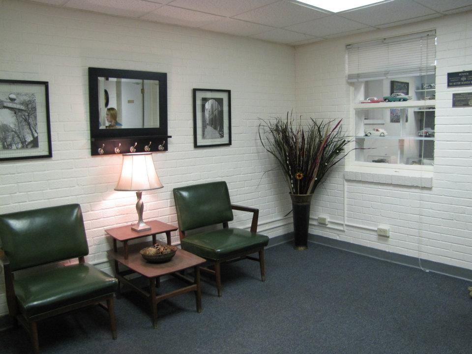 A waiting room with green chairs and a lamp