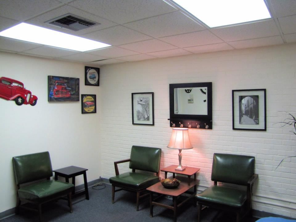 A waiting room with green chairs and a red car on the wall