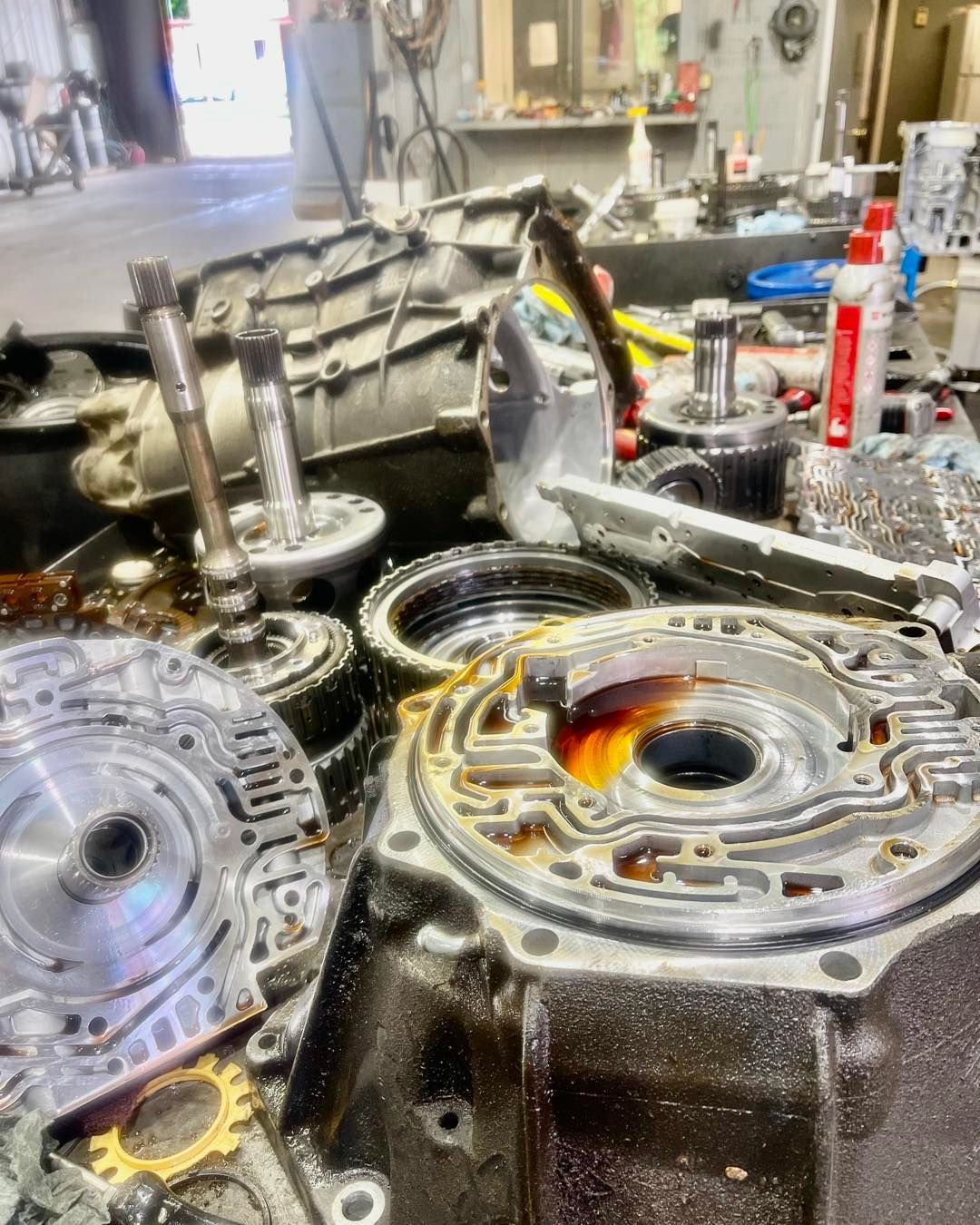 A bunch of mechanical parts are sitting on a table in a garage.