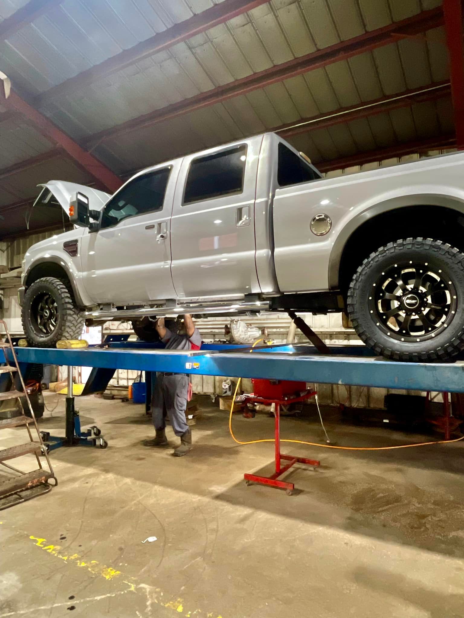 A truck is sitting on top of a lift in a garage.