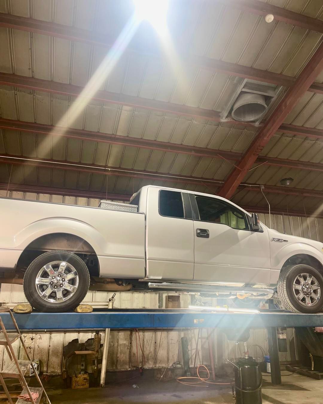A white truck is sitting on top of a lift in a garage.