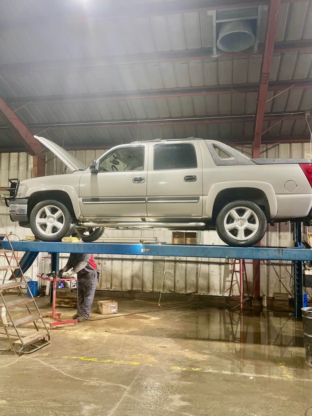 A truck is sitting on top of a lift in a garage.
