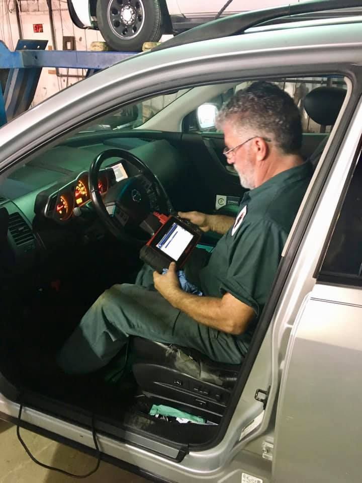 A man is sitting in a car using a tablet.