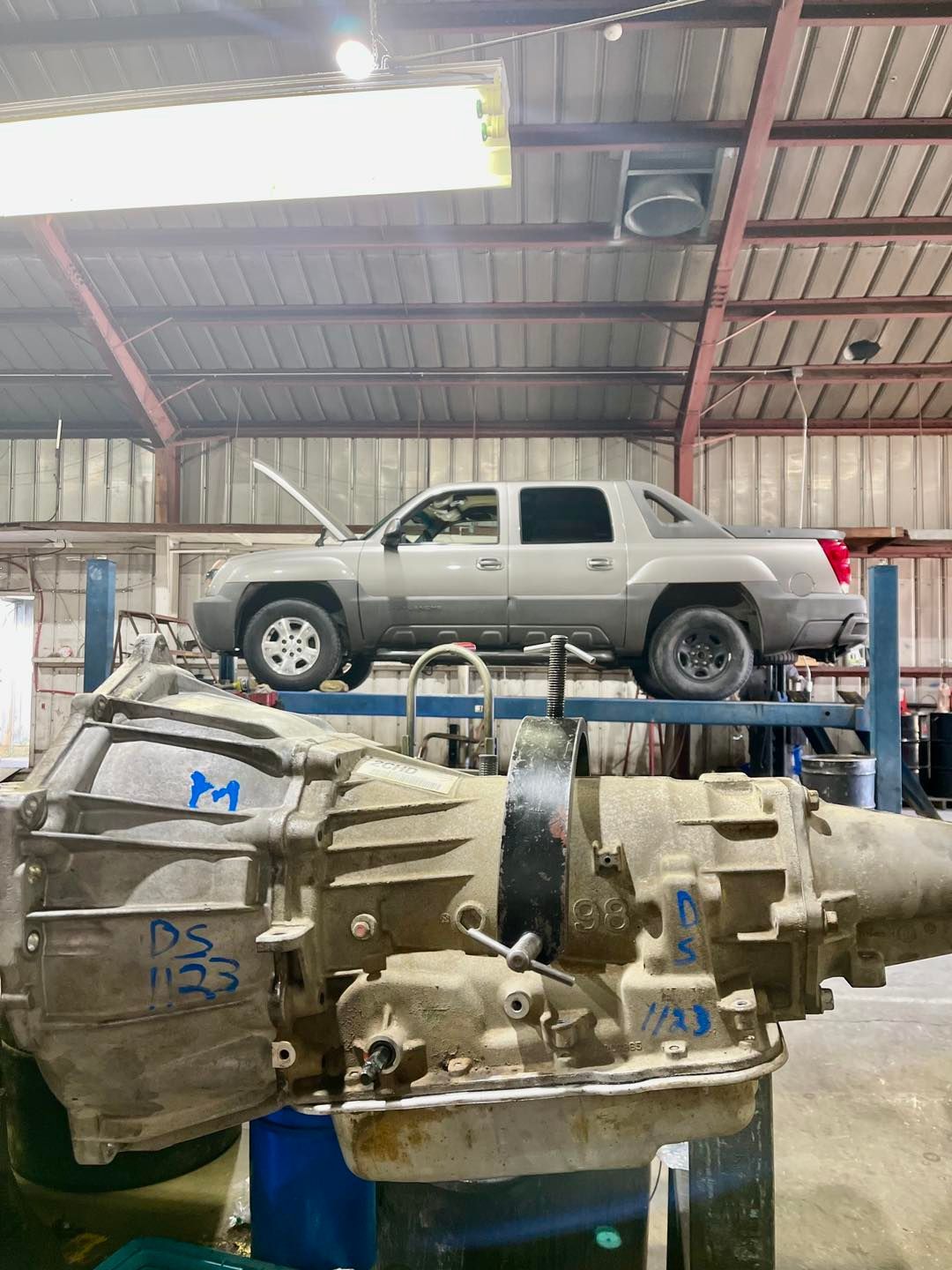 A truck is sitting on top of a gearbox in a garage.