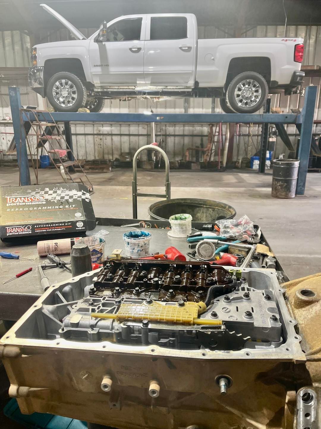 A white truck is parked on a lift in a garage.