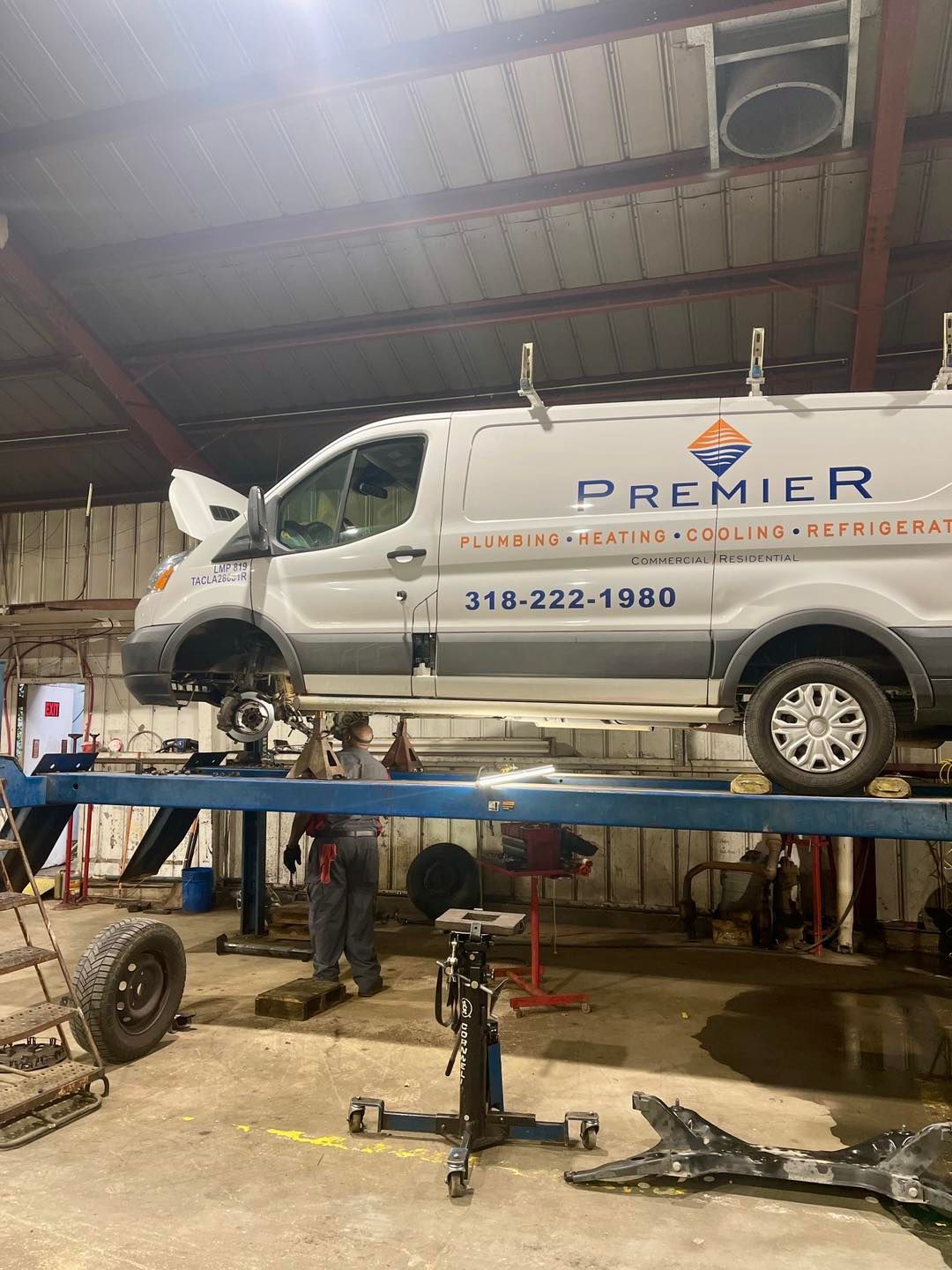A white van is sitting on top of a lift in a garage.