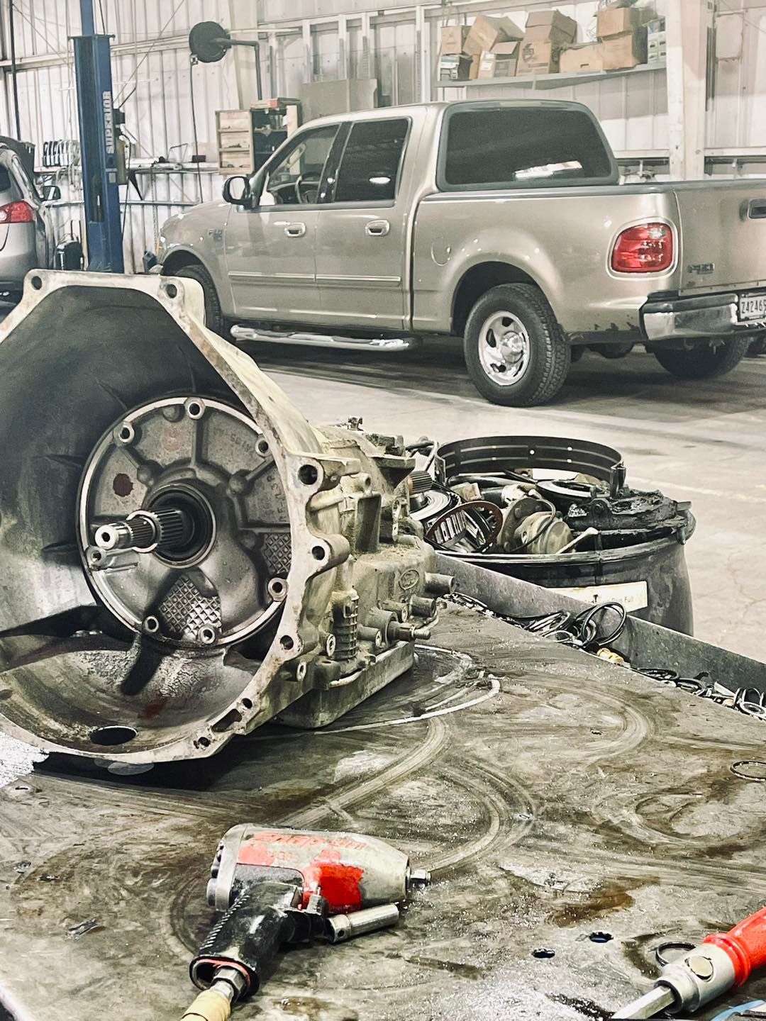 A truck is sitting in a garage next to a broken gearbox.