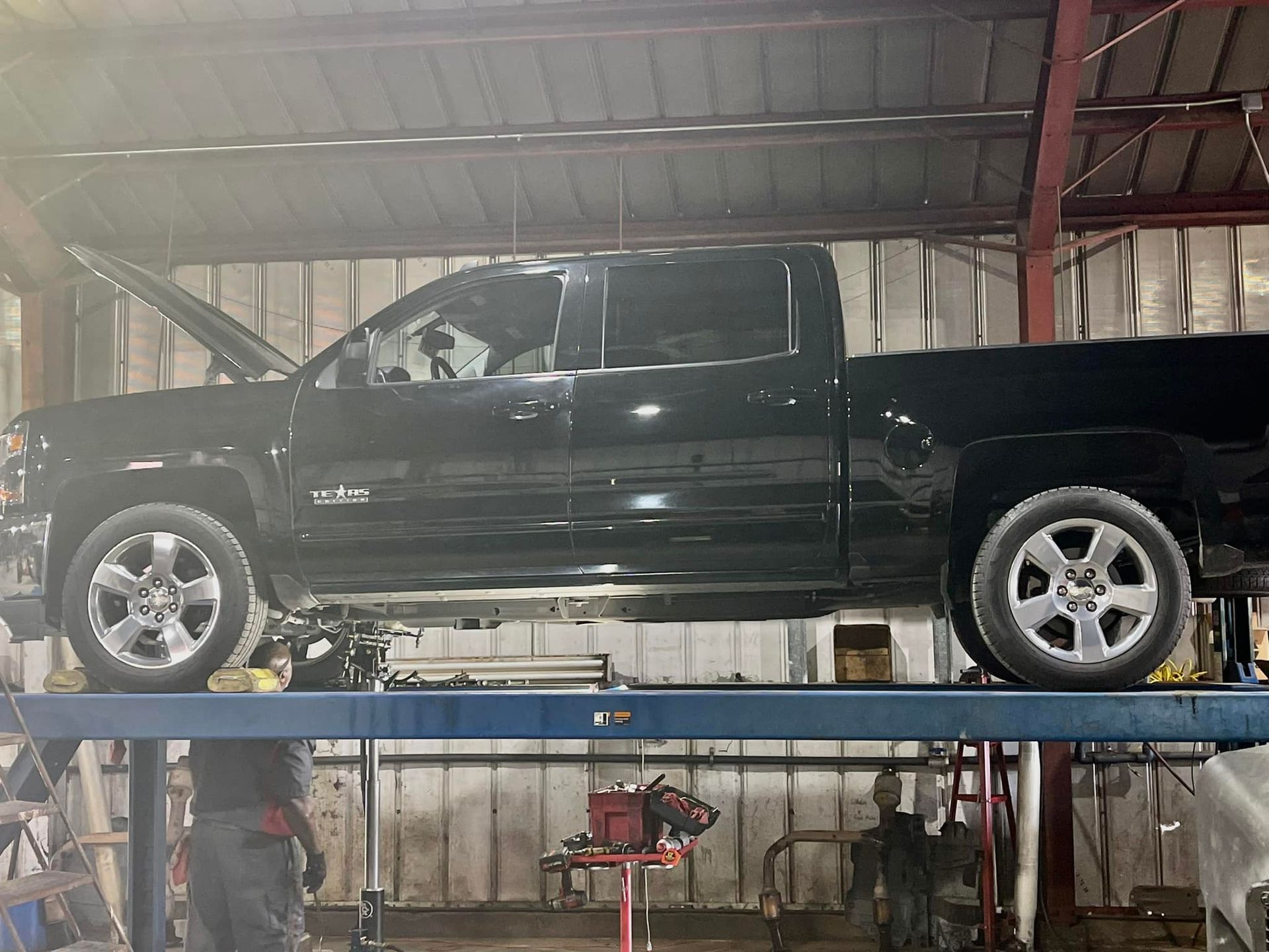 A black truck is parked on a lift in a garage.
