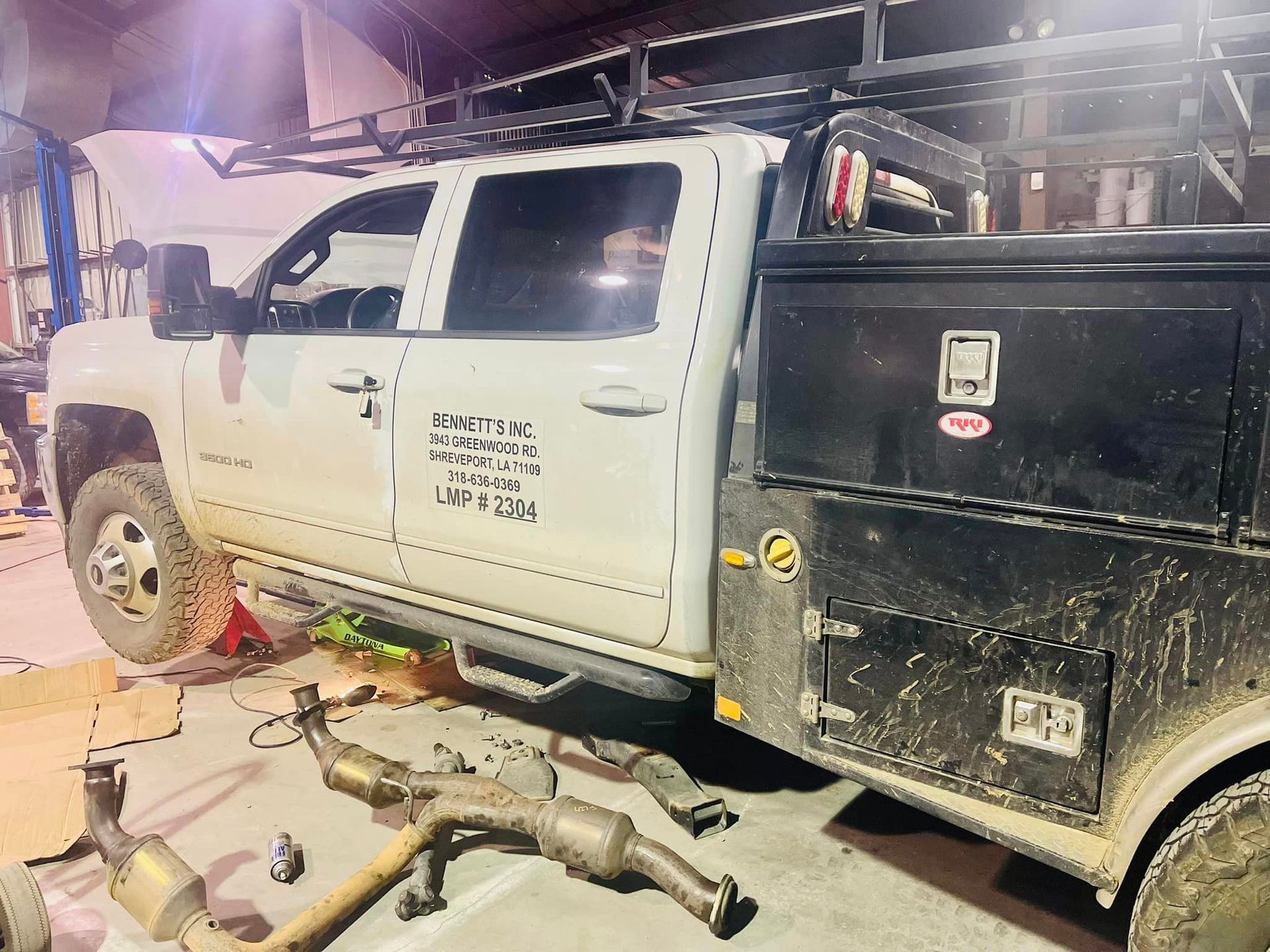 A white truck is parked next to a black truck in a garage.