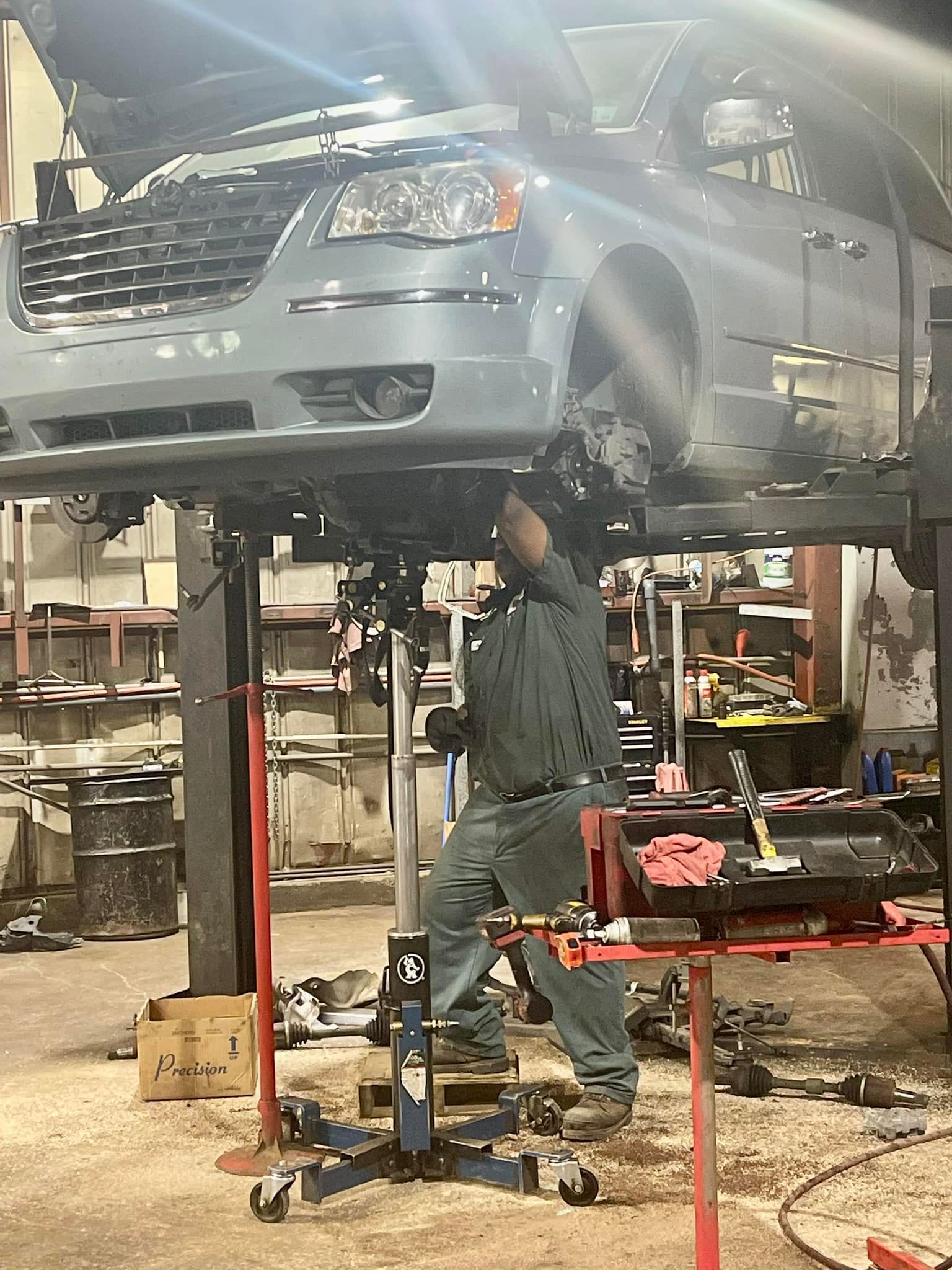A man is working on a car on a lift in a garage.