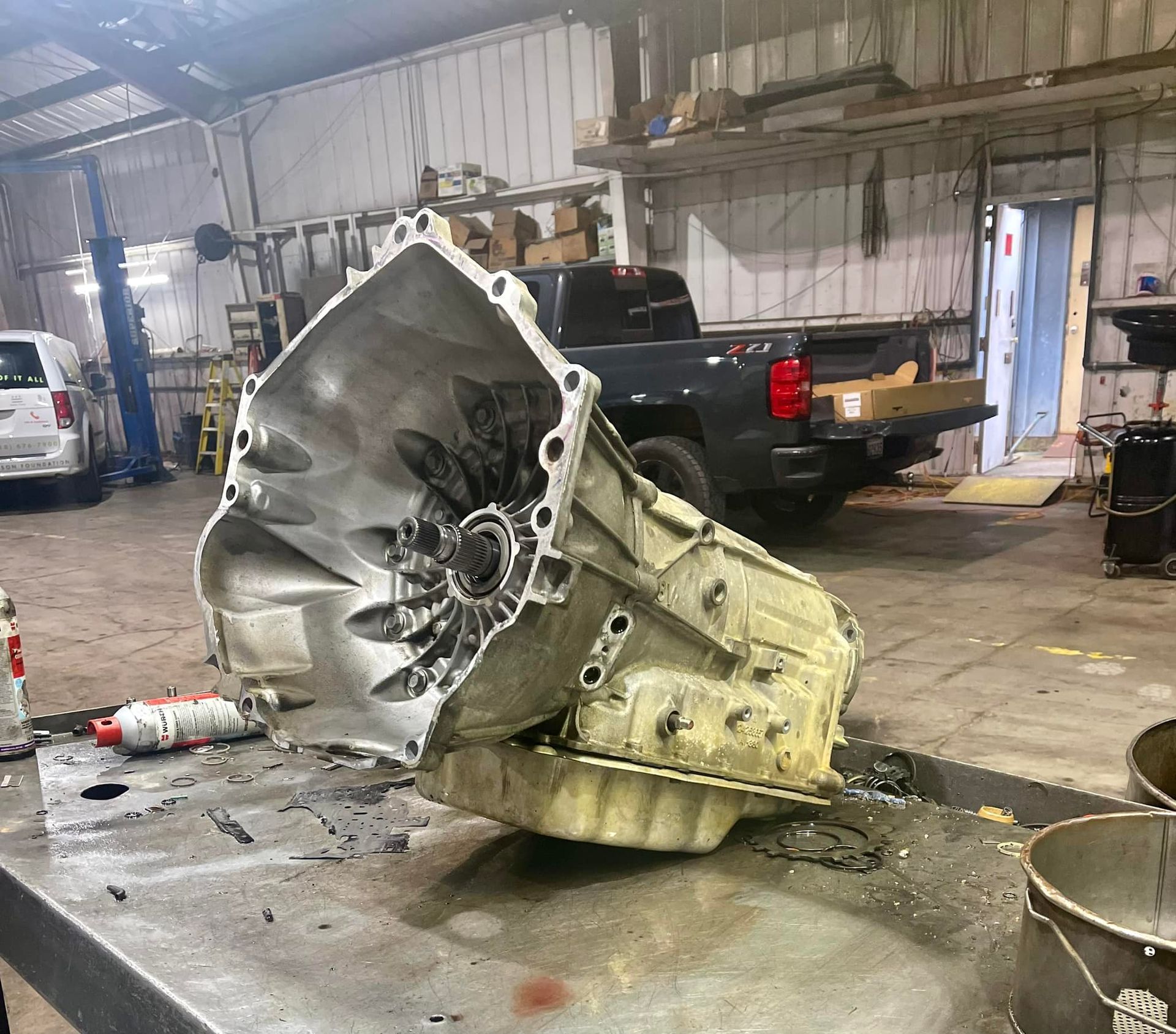 A transmission is sitting on a table in a garage next to a truck.