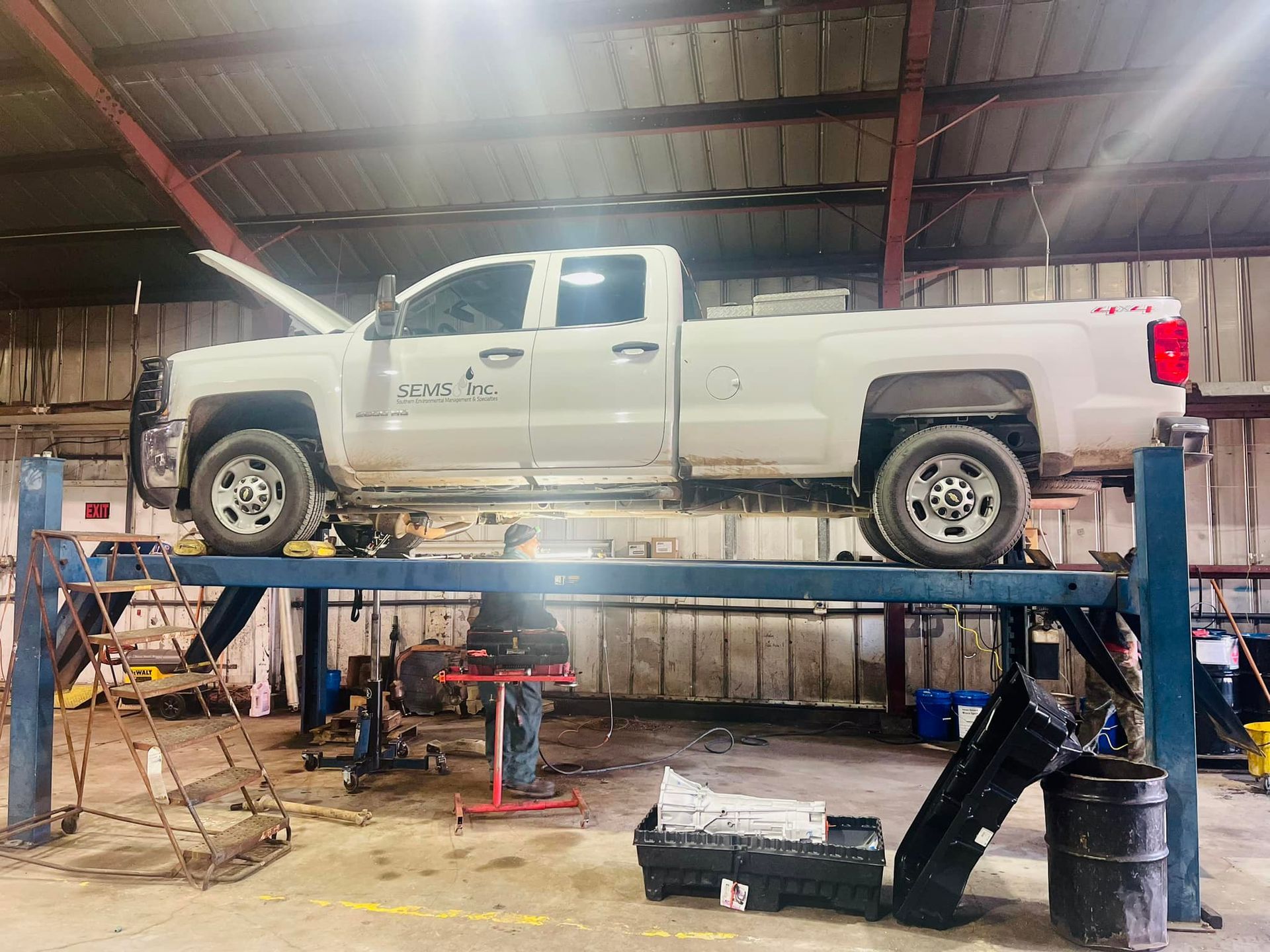 A white truck is sitting on top of a lift in a garage.