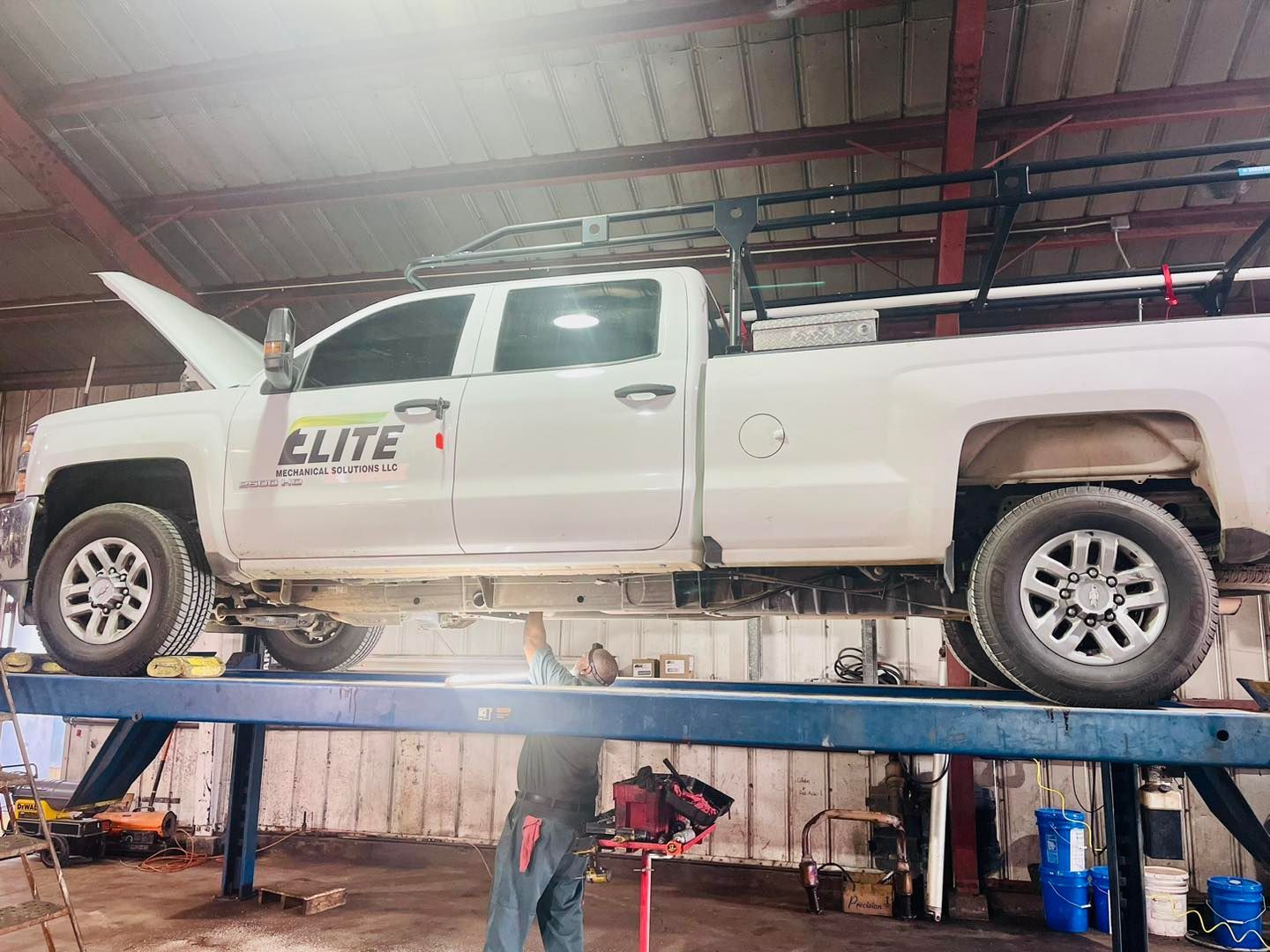 A white truck is sitting on top of a lift in a garage.