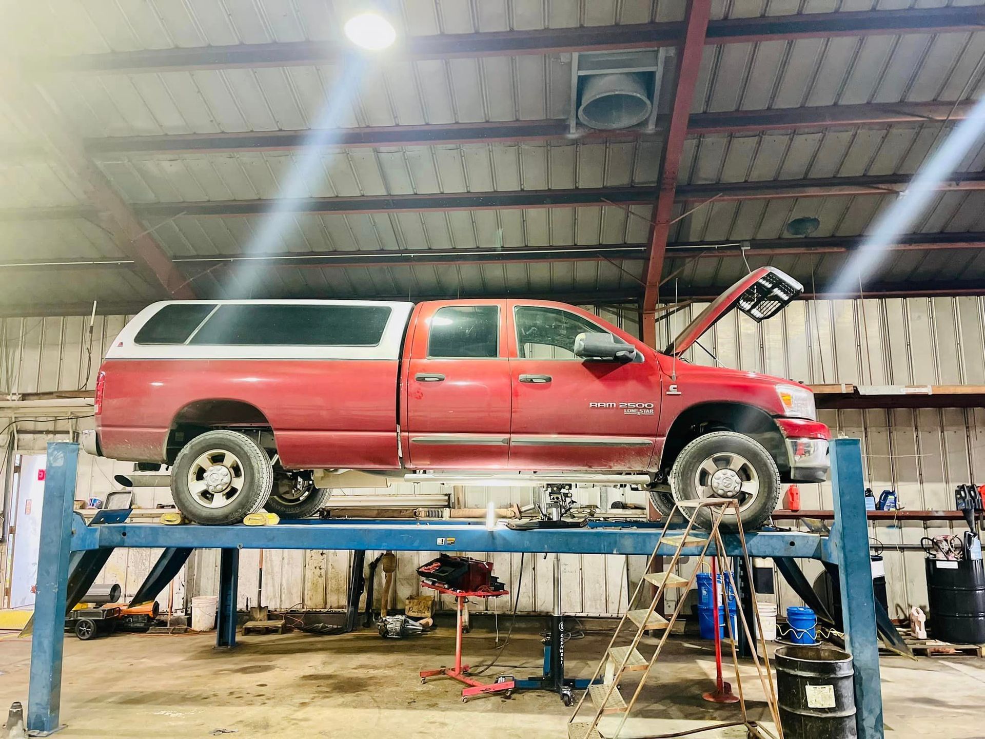 A red truck is parked on a lift in a garage.