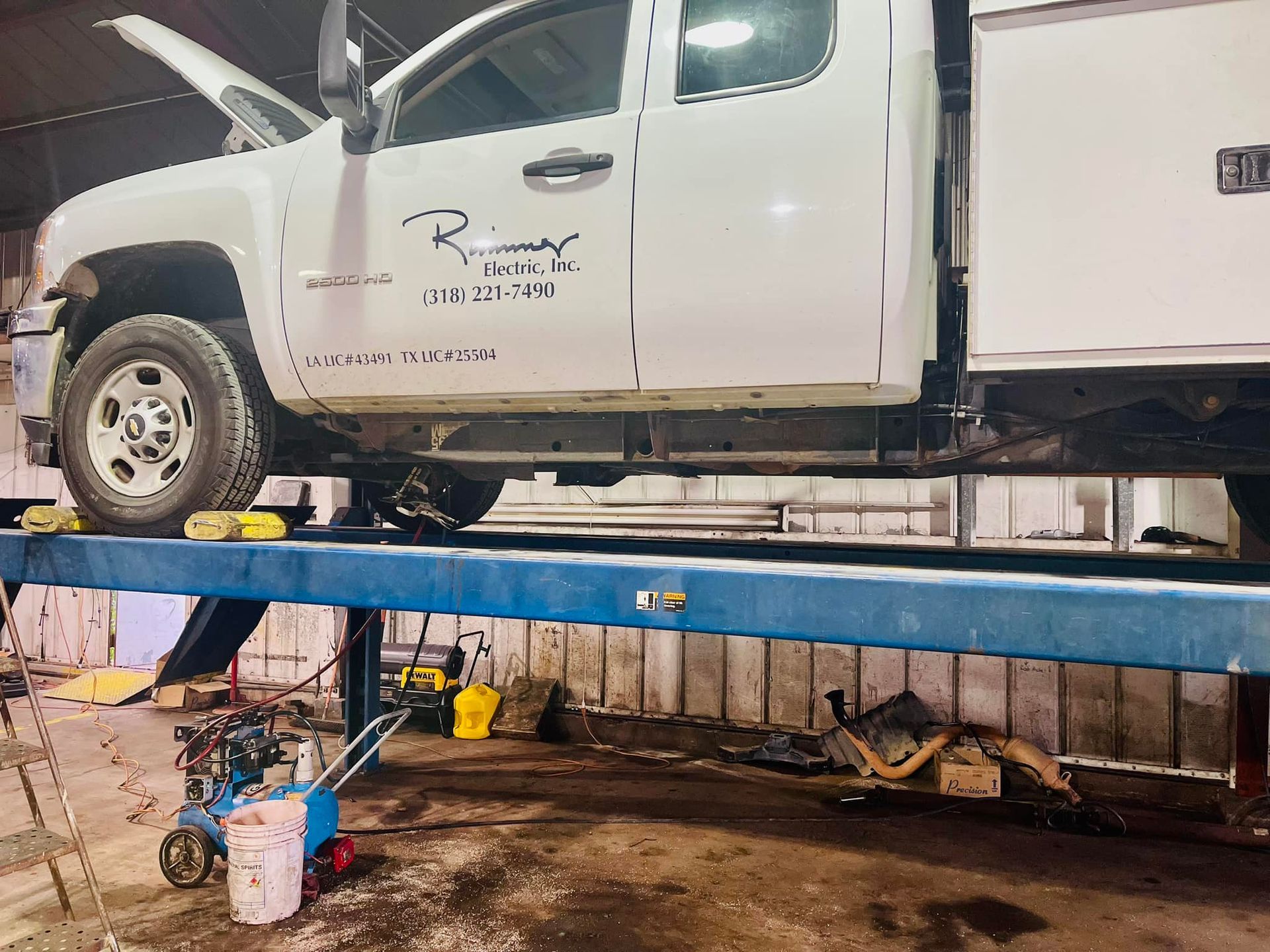 A white truck is sitting on a lift in a garage.