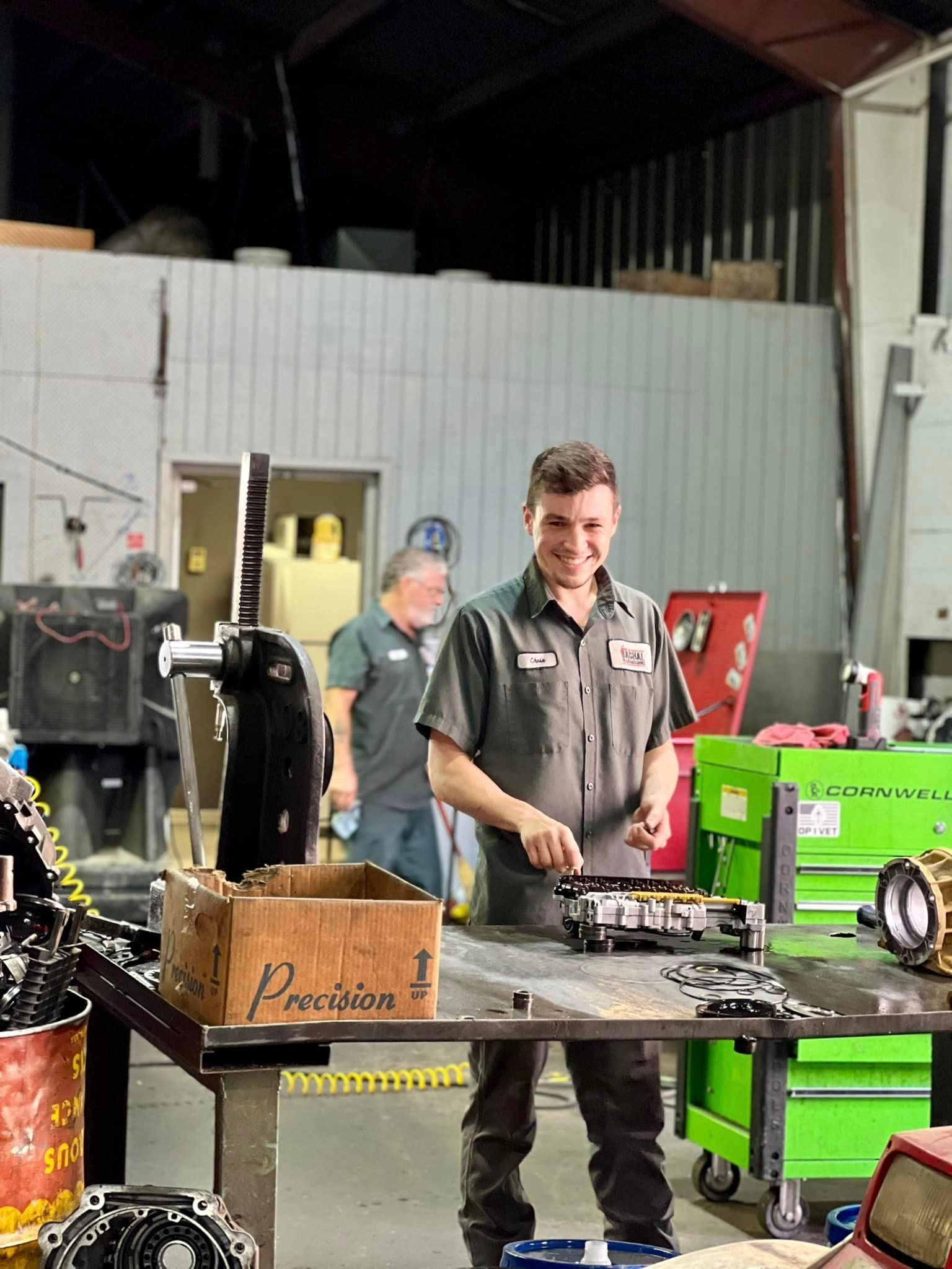 A man is standing at a table in a garage working on a machine.