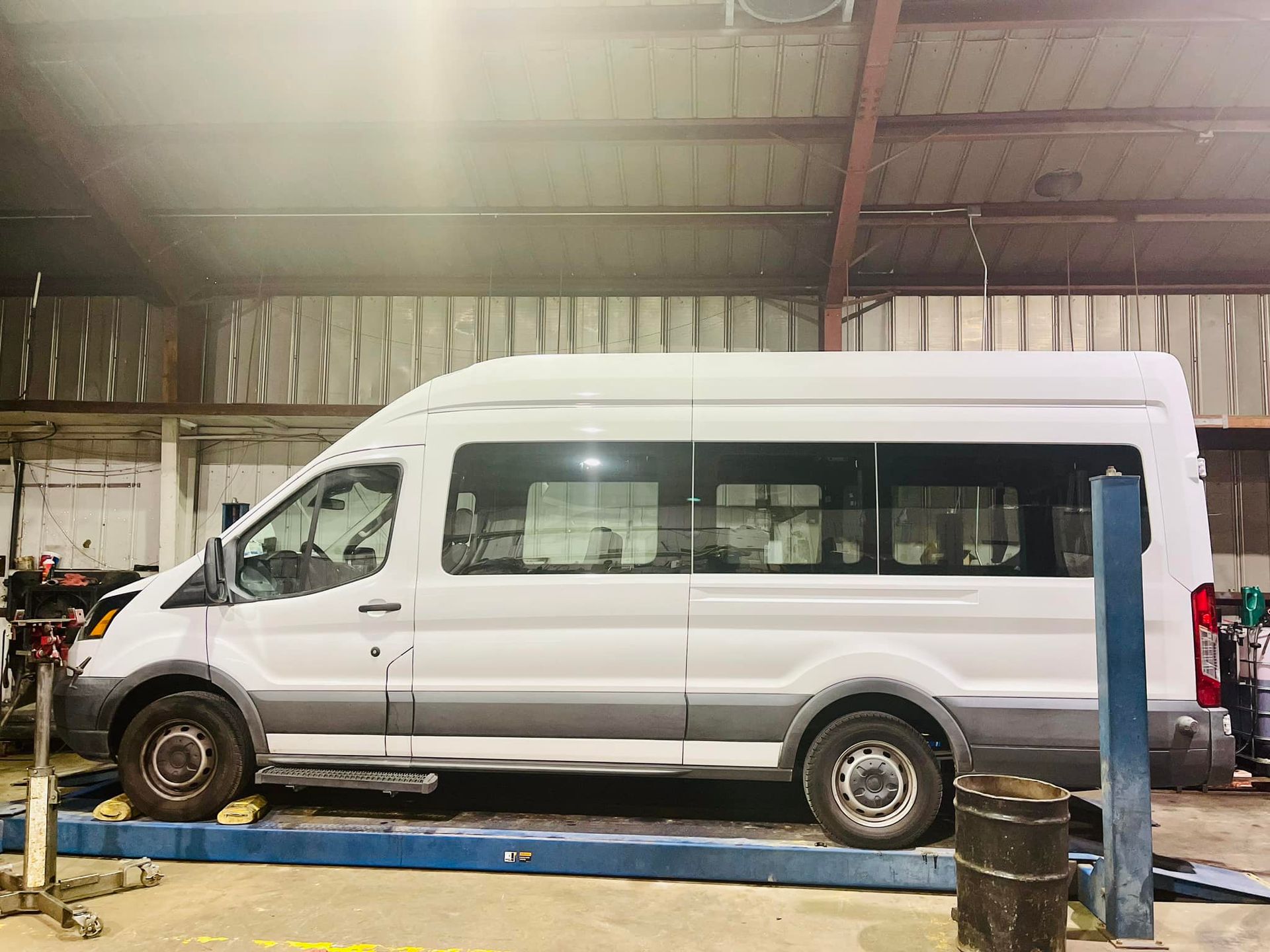 A white van is parked on a lift in a garage.