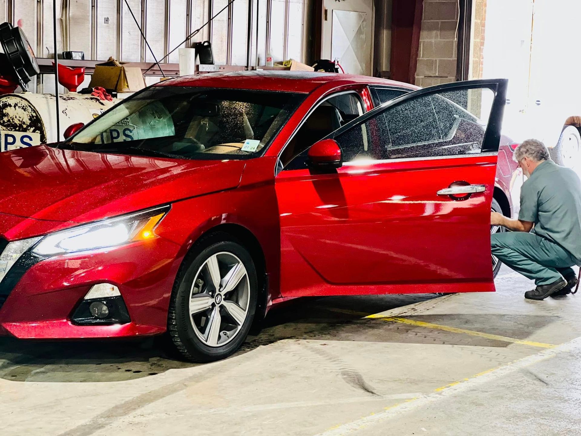 A man is cleaning a red car in a garage.