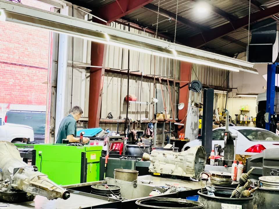A man is working on a green machine in a garage.