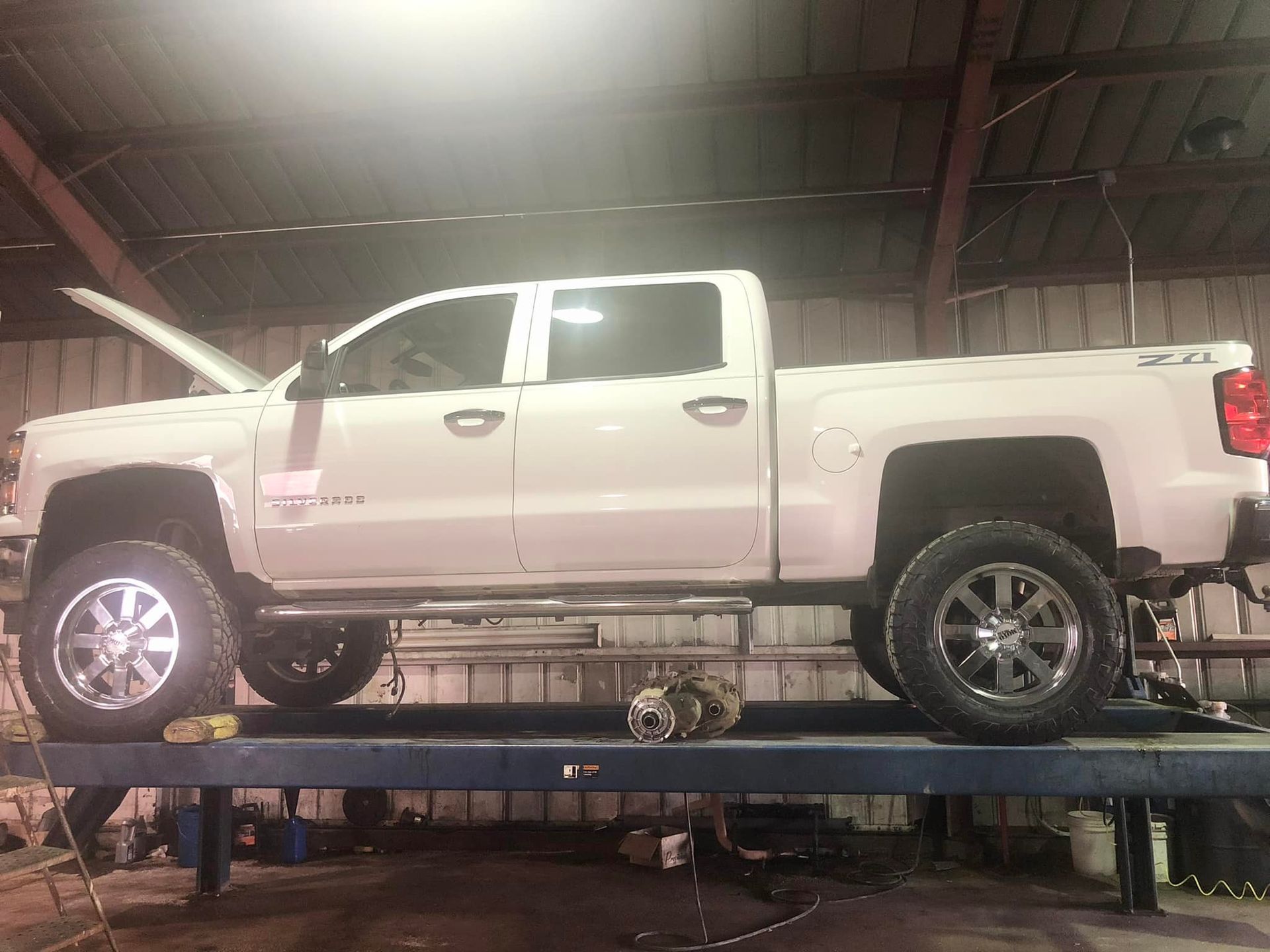 A white truck is parked on a lift in a garage.