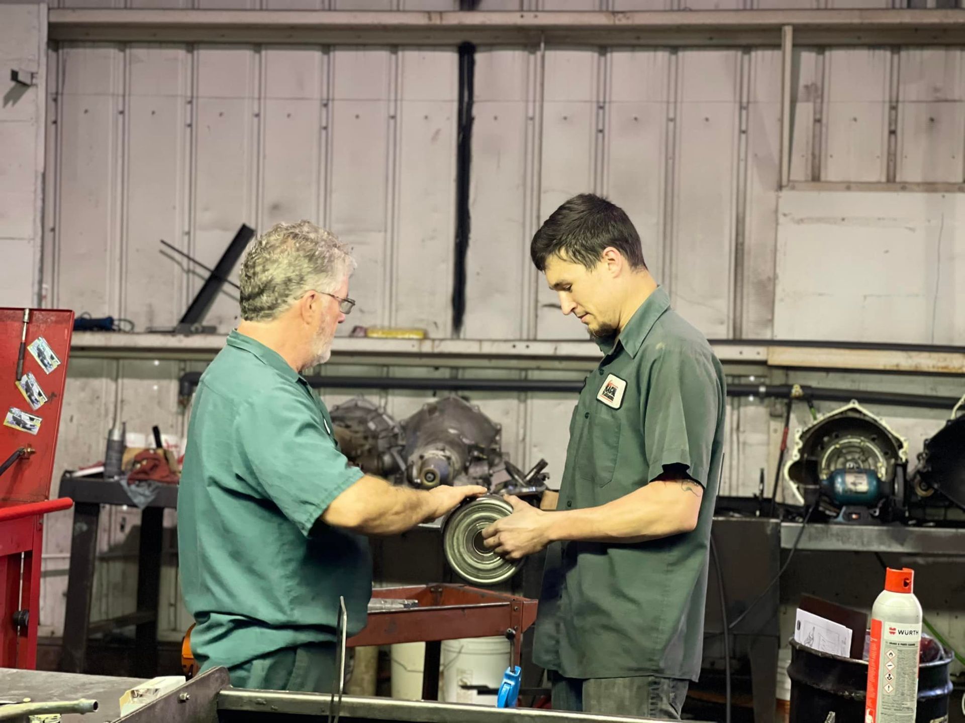 Two men are working on a machine in a garage.