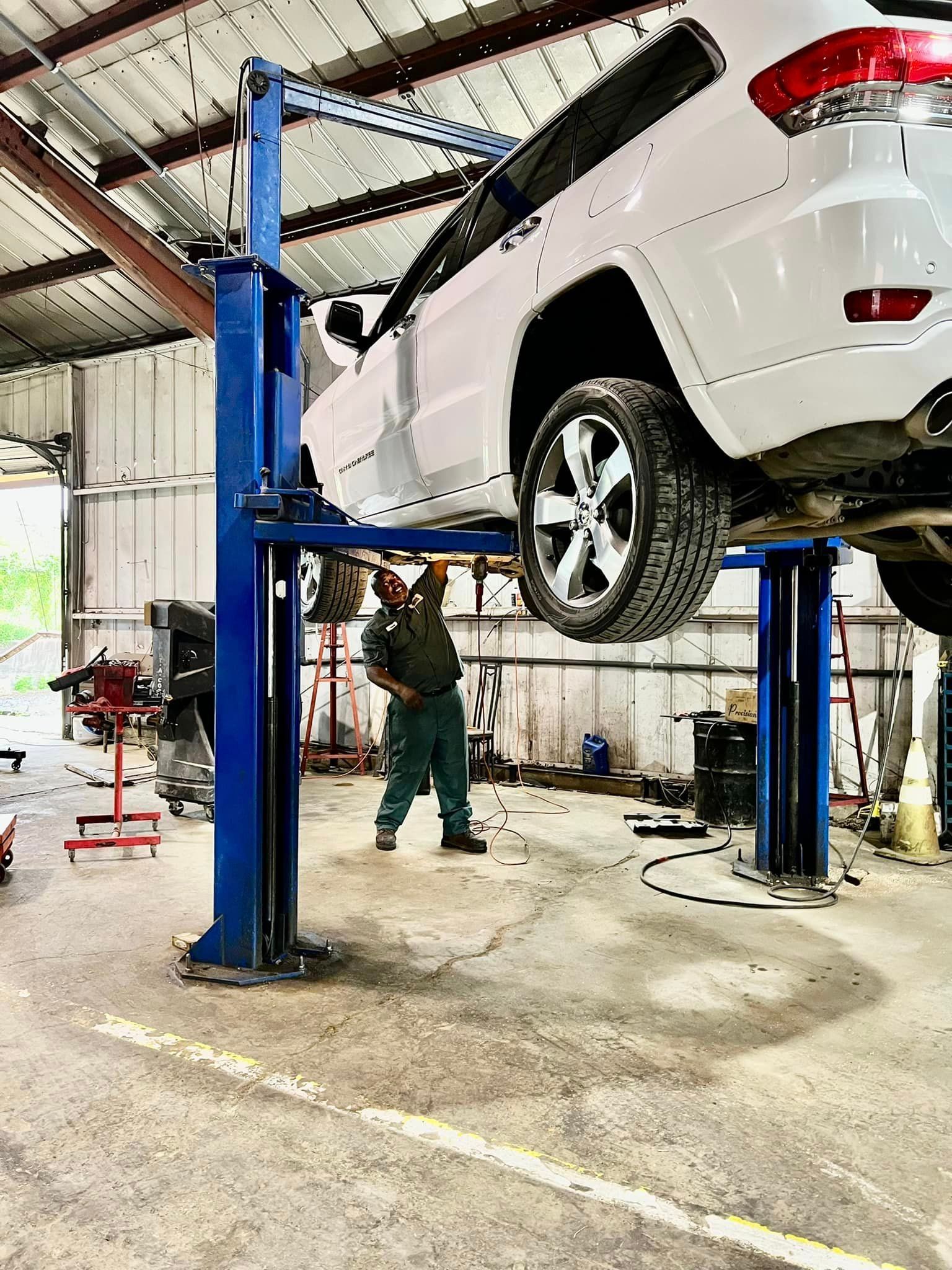 A man is working on a car on a lift in a garage.