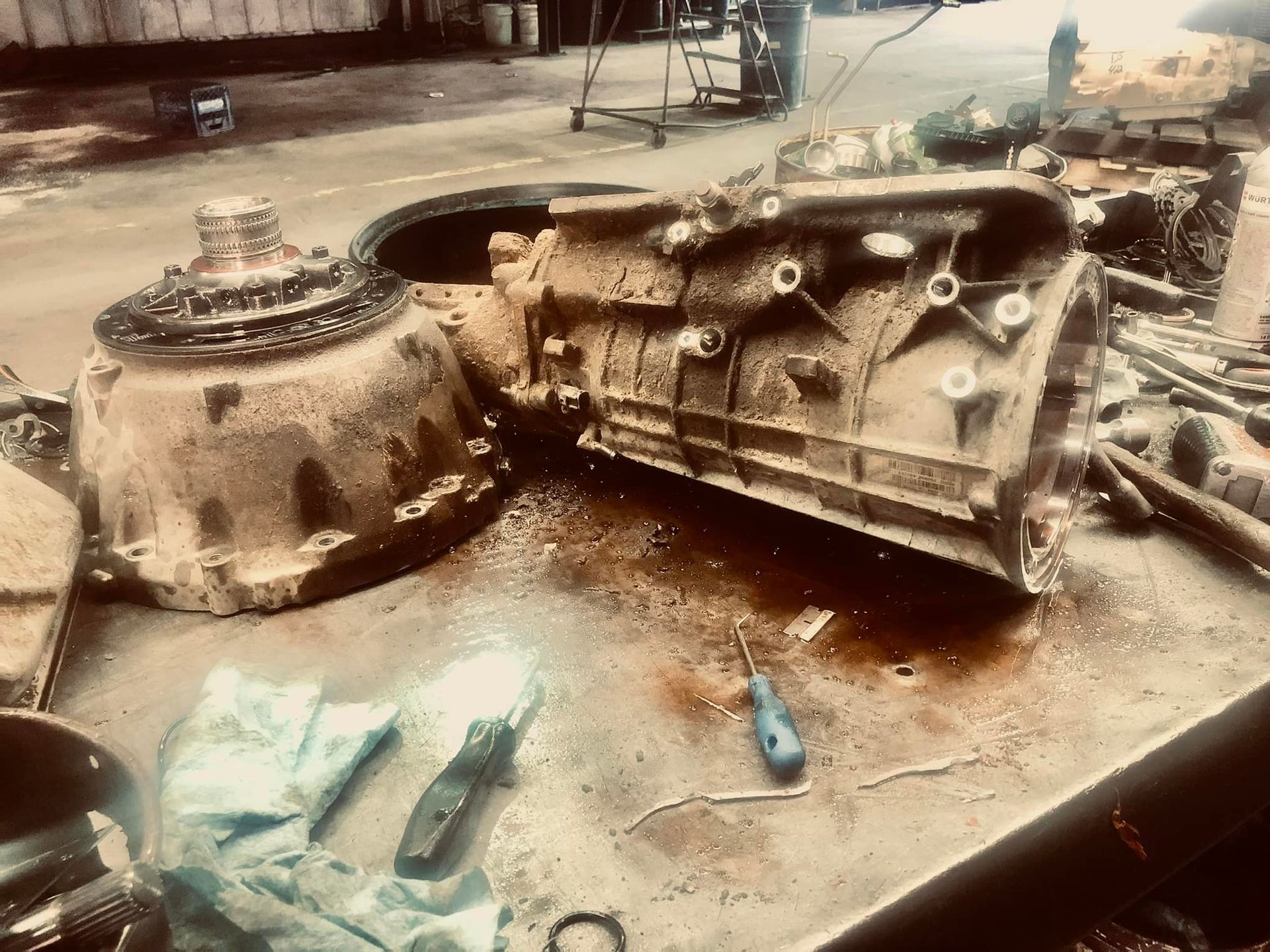 A dirty piece of metal is sitting on a table next to a screwdriver.