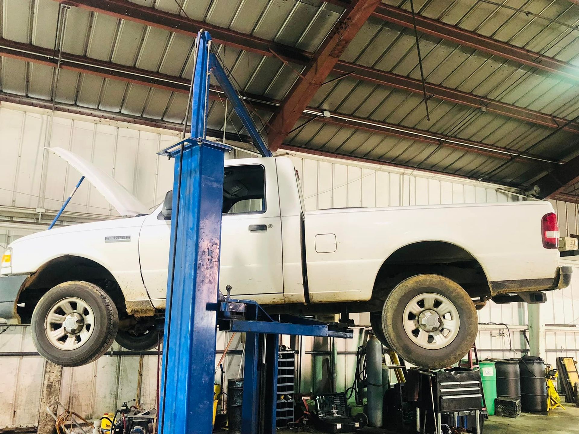 A white truck is sitting on a lift in a garage.