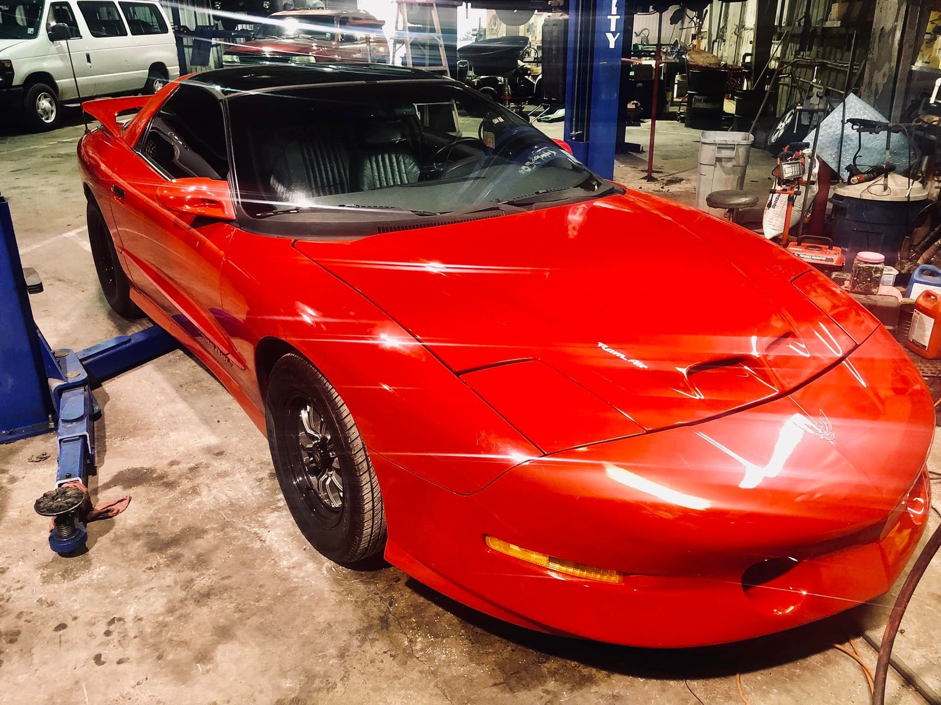 A red sports car is sitting on a lift in a garage.