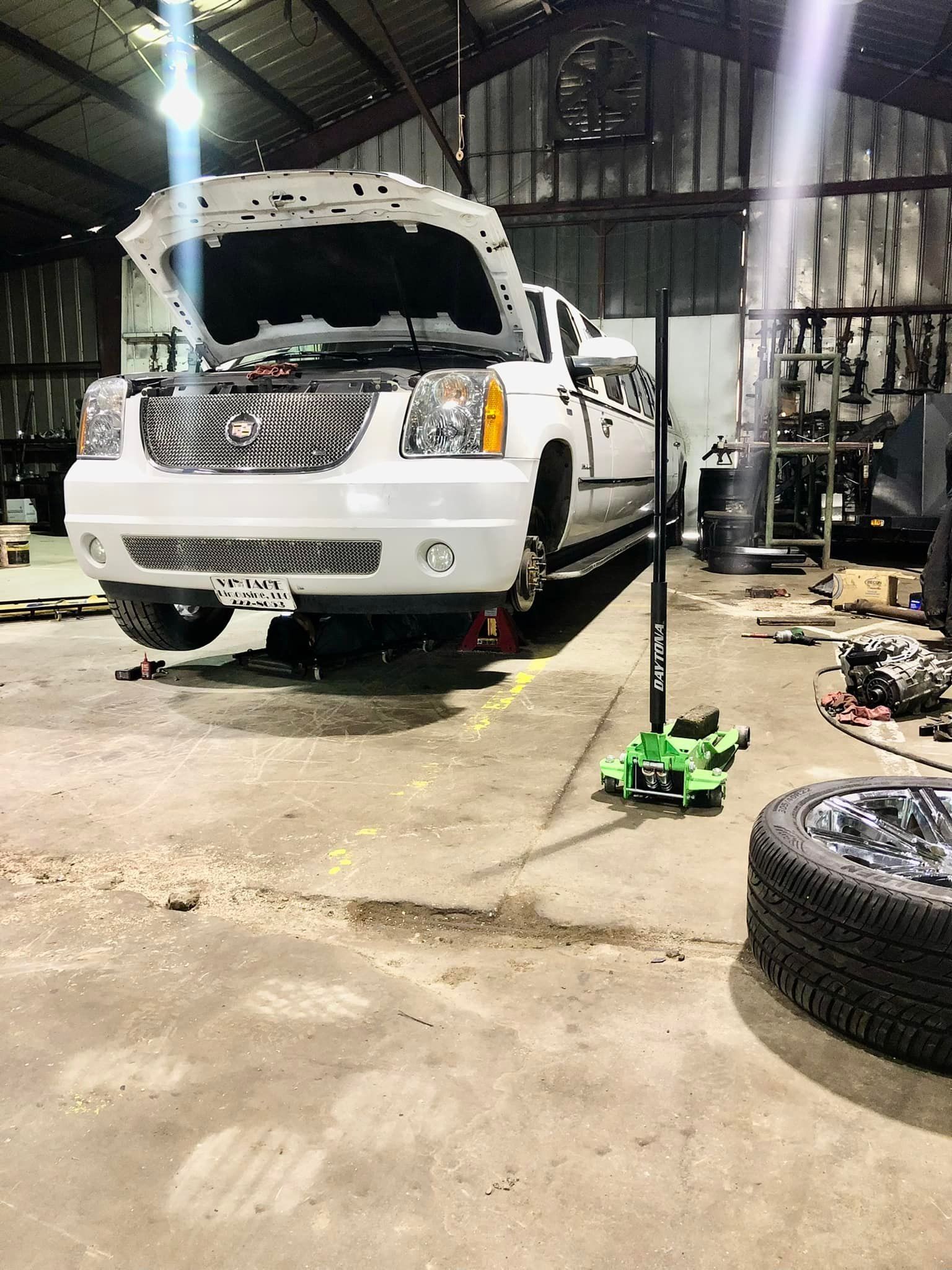 A white truck with the hood up is parked in a garage.