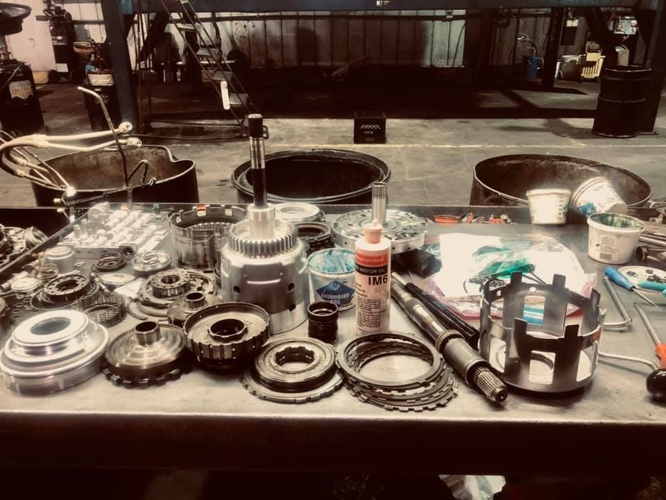 A table with a bunch of gears and a bottle of oil on it.