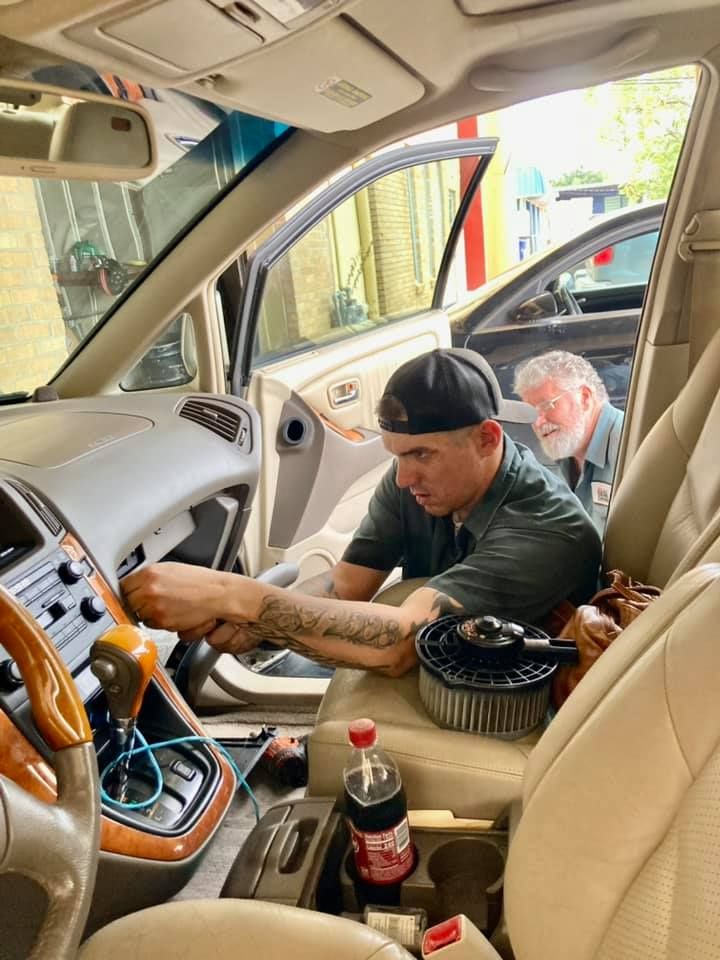 A man is working on the dashboard of a car.