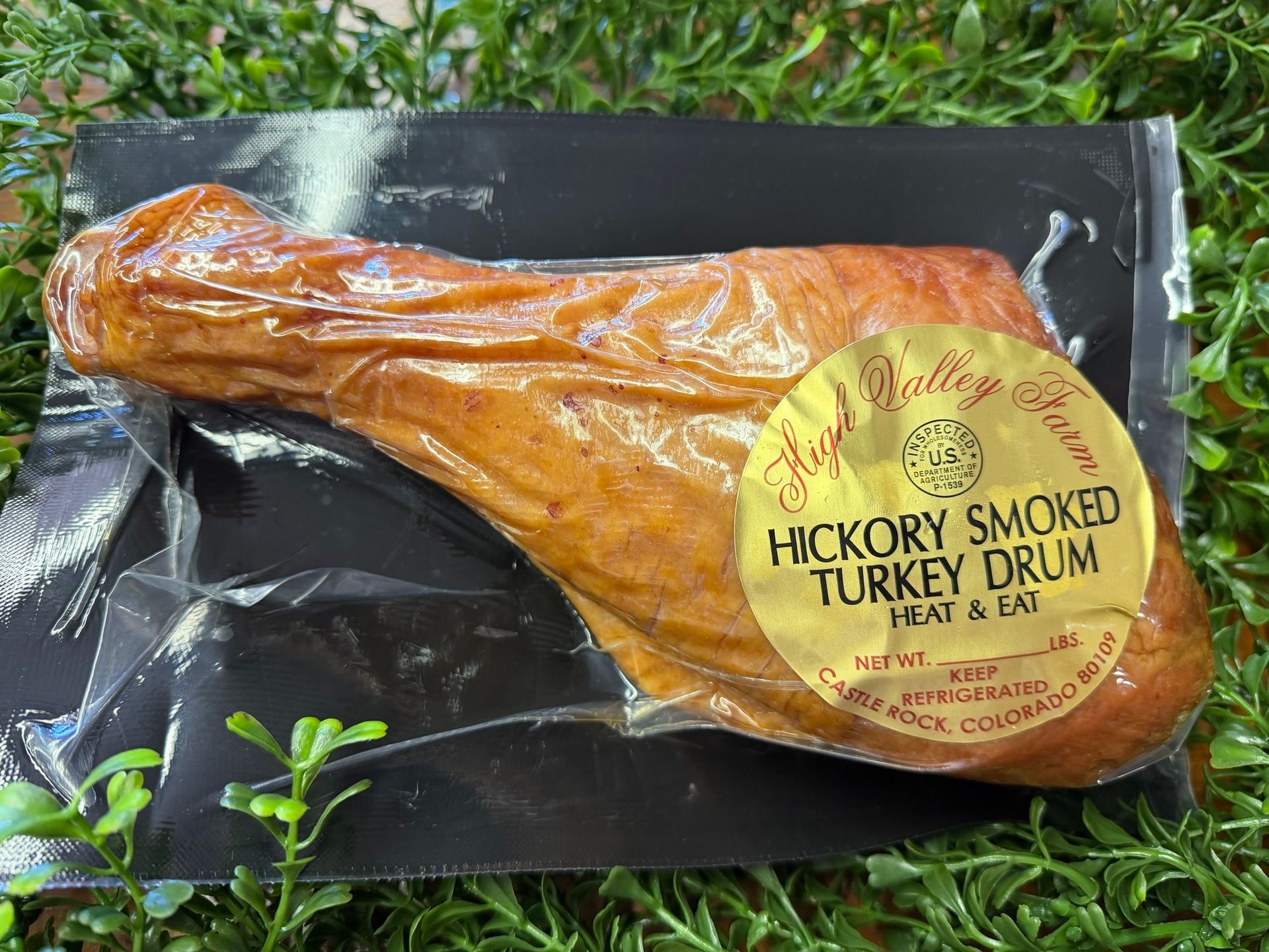 Packaged hickory smoked turkey drum on a black tray, wrapped in clear plastic with a yellow label.