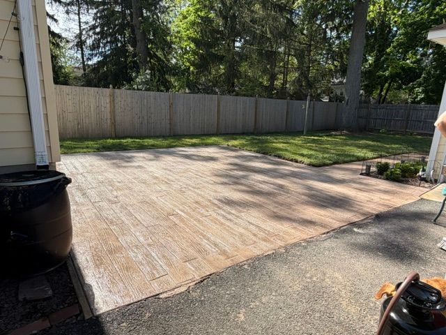 Wooden backyard deck beside a wooden fence and trees, with a trash can in the foreground.