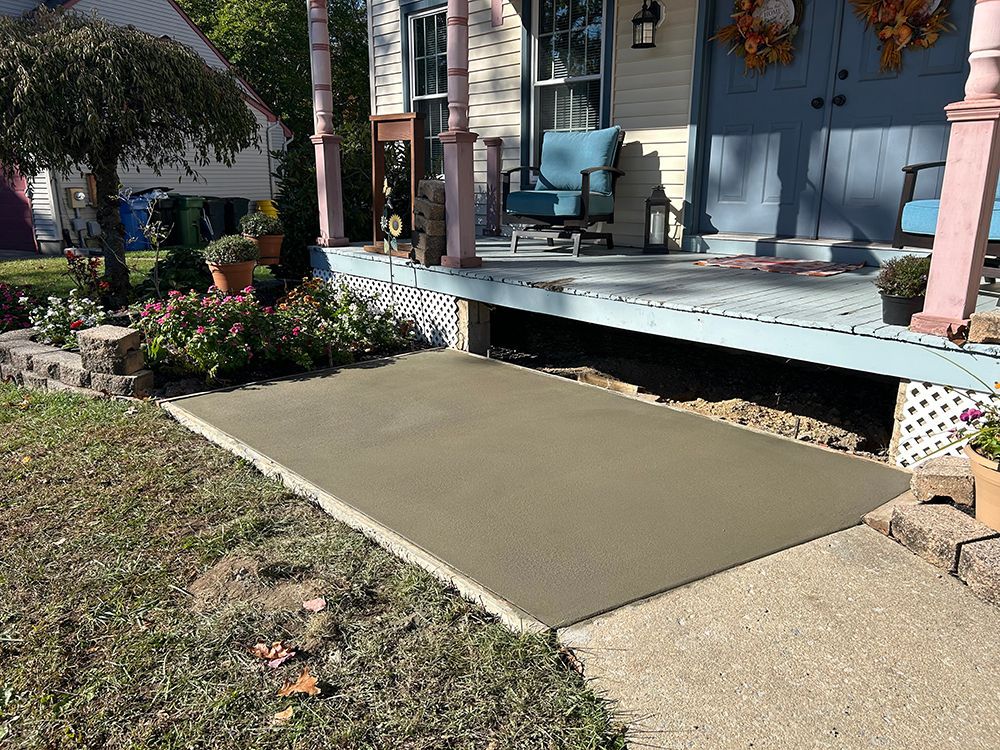 New concrete ramp leading to a porch. House with blue door and pink pillars.