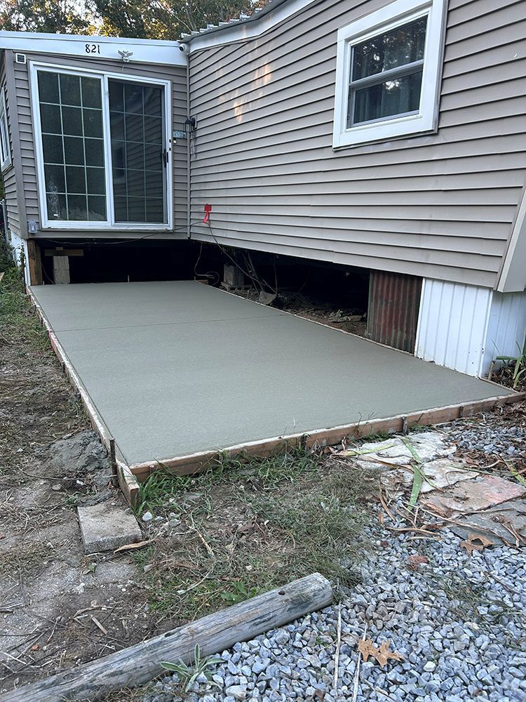 Newly poured concrete patio next to a house with a sliding glass door.