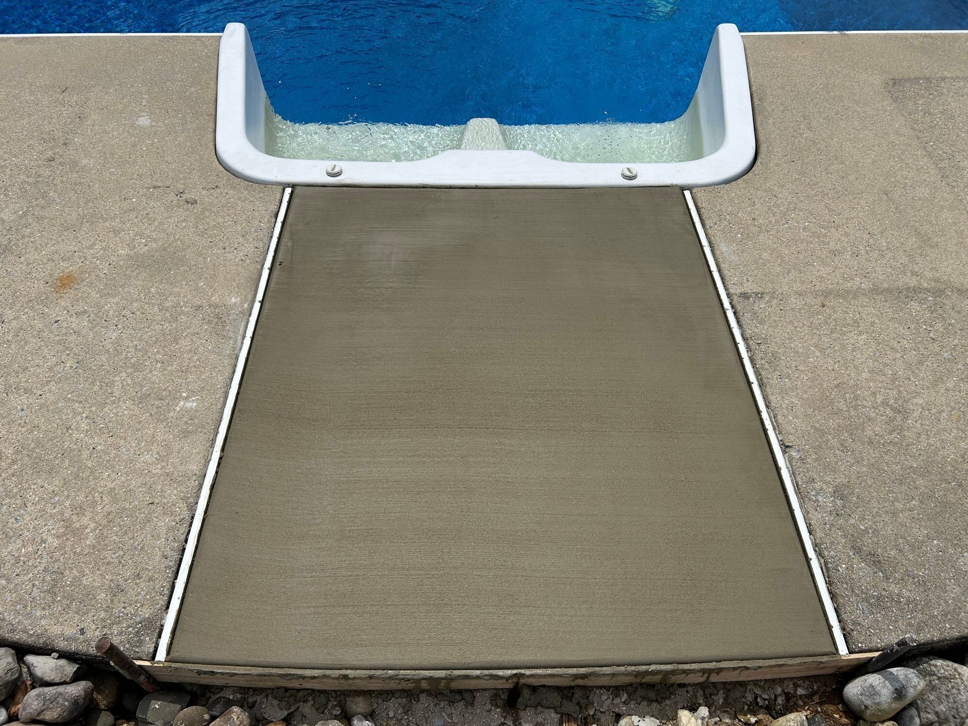 Concrete walkway leading to a pool, with a freshly poured, lighter section.