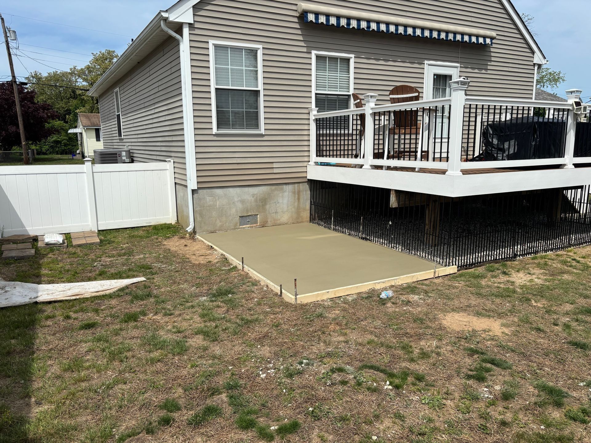 A newly poured concrete patio next to a house with a deck.