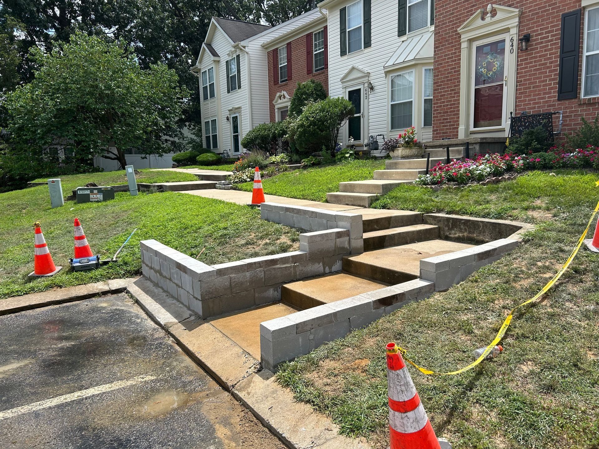 Concrete steps and retaining walls in front of townhouses; construction cones present.