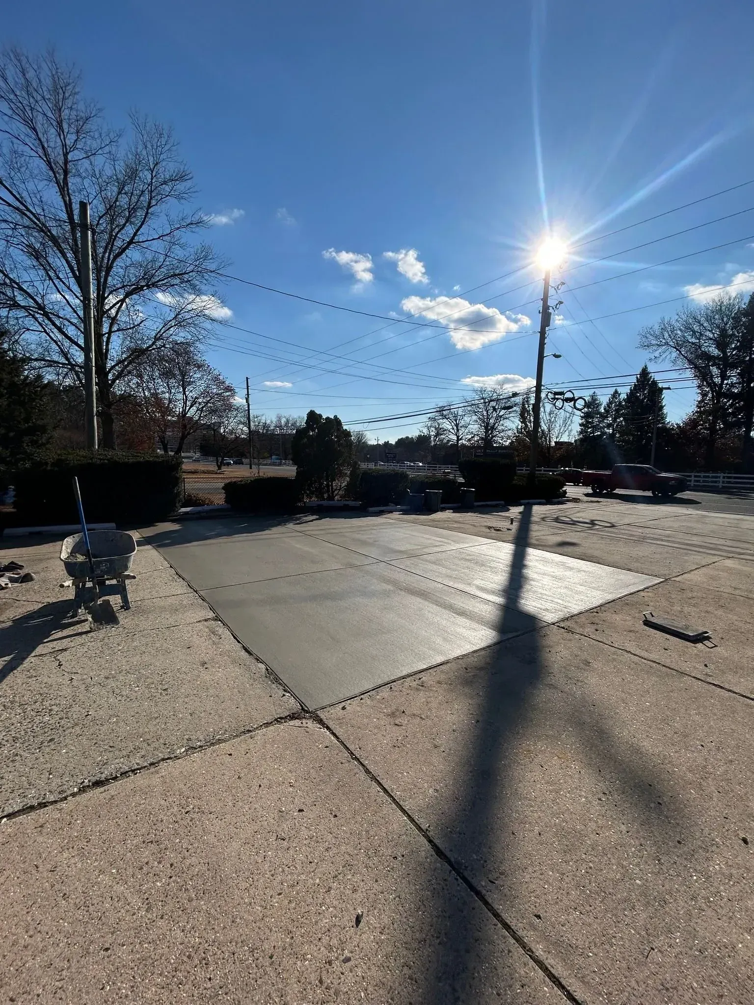 Concrete walkway with bright sun, blue sky, and string lights overhead.