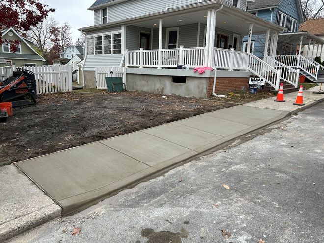 Sunny day with a newly poured concrete walkway, casting long shadows.