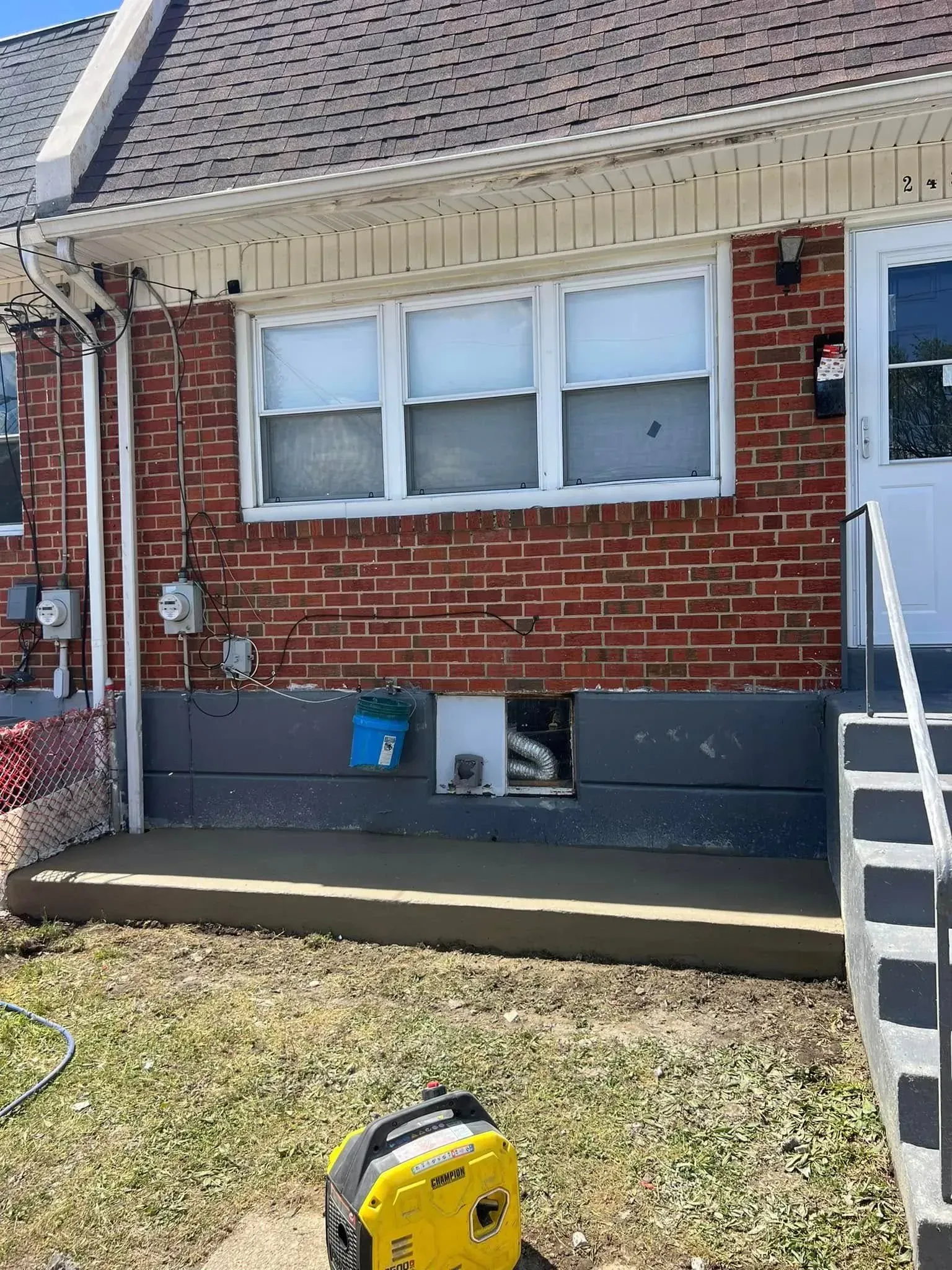 Brick house exterior with window, concrete slab, gray foundation, and generator.