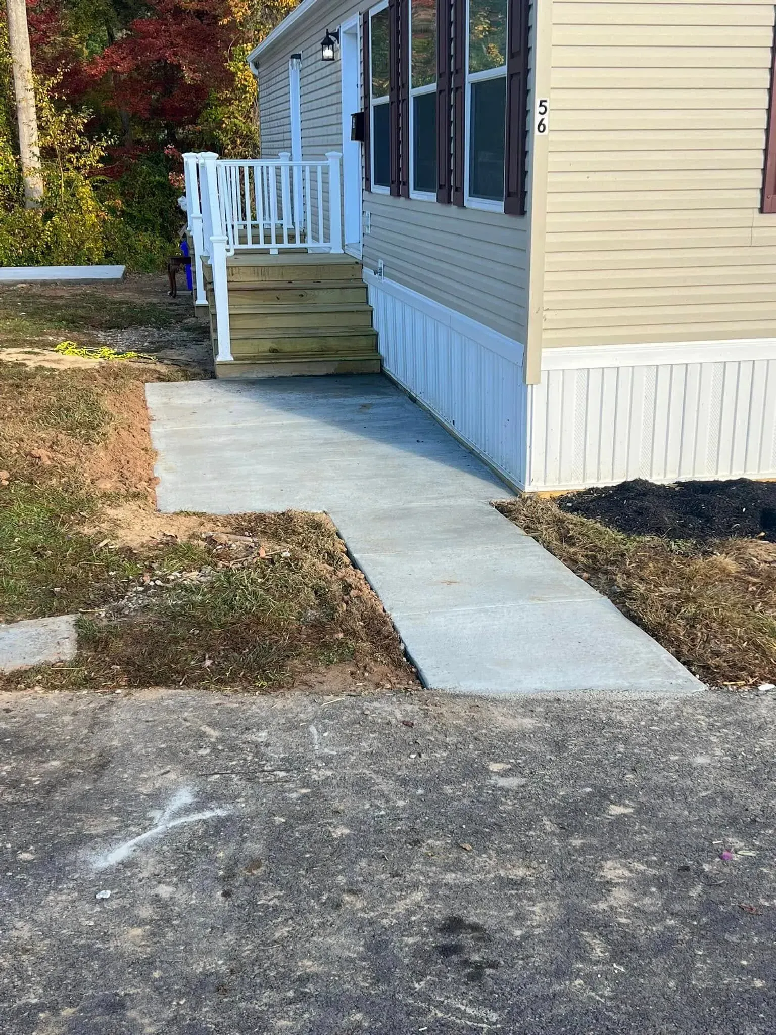 Concrete walkway leading to steps up to a beige mobile home.