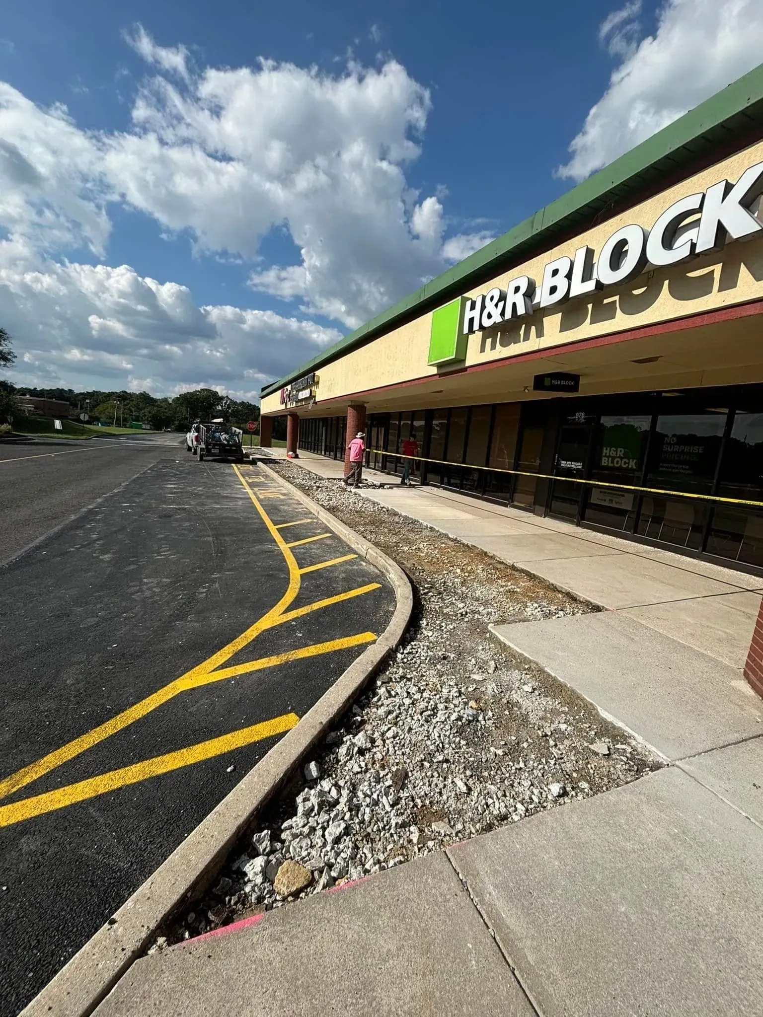 Exterior of an H&R Block storefront in a shopping center with parking.