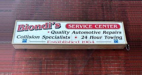 Biondi’s Service Center sign on a red brick wall, advertising auto repairs, collision work, and 24-hour towing